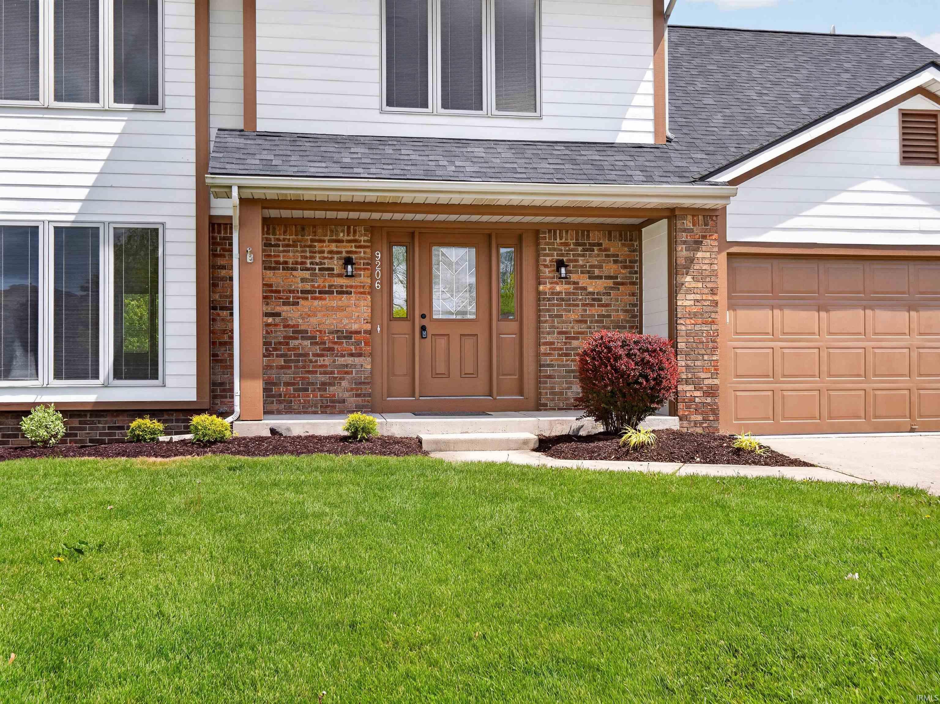 Two-story residence featuring white siding and brick accents
