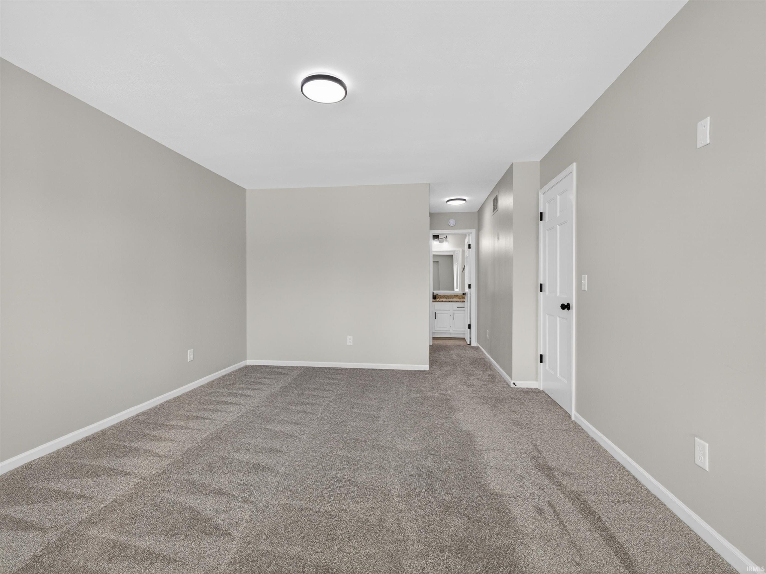 Spacious room featuring neutral carpeting and light gray walls