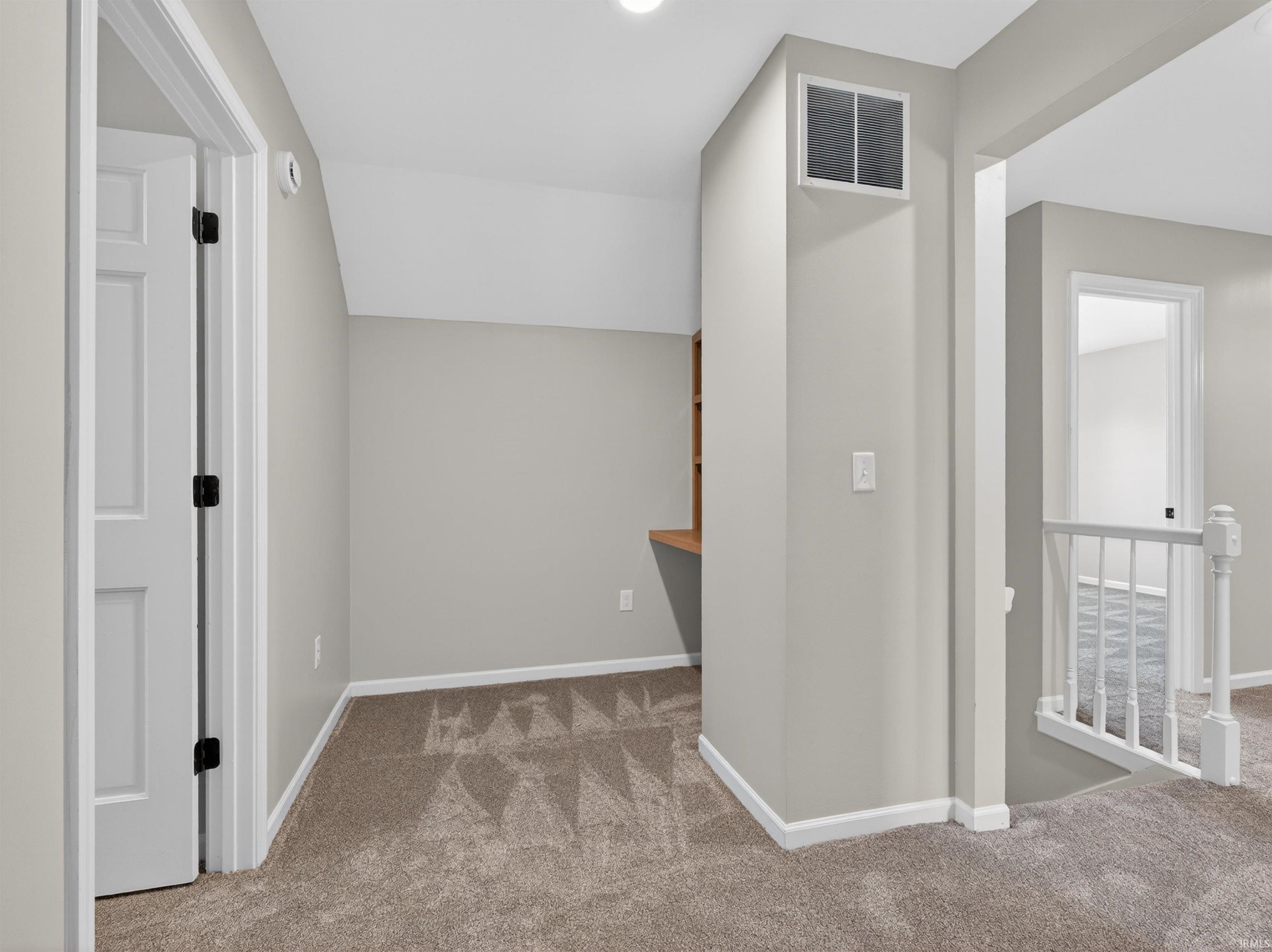 Carpeted room with a built-in wood desk and shelving