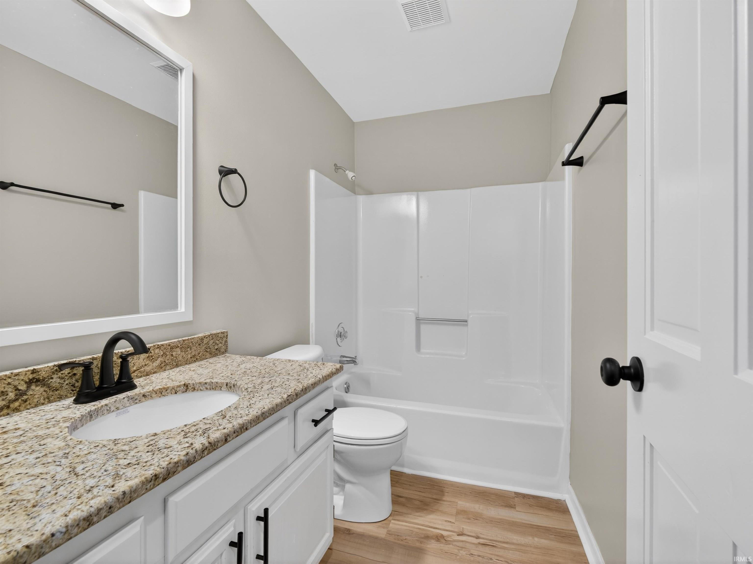 Bathroom featuring a white vanity with a granite-look countertop, undermount sink, and matte black fixtures