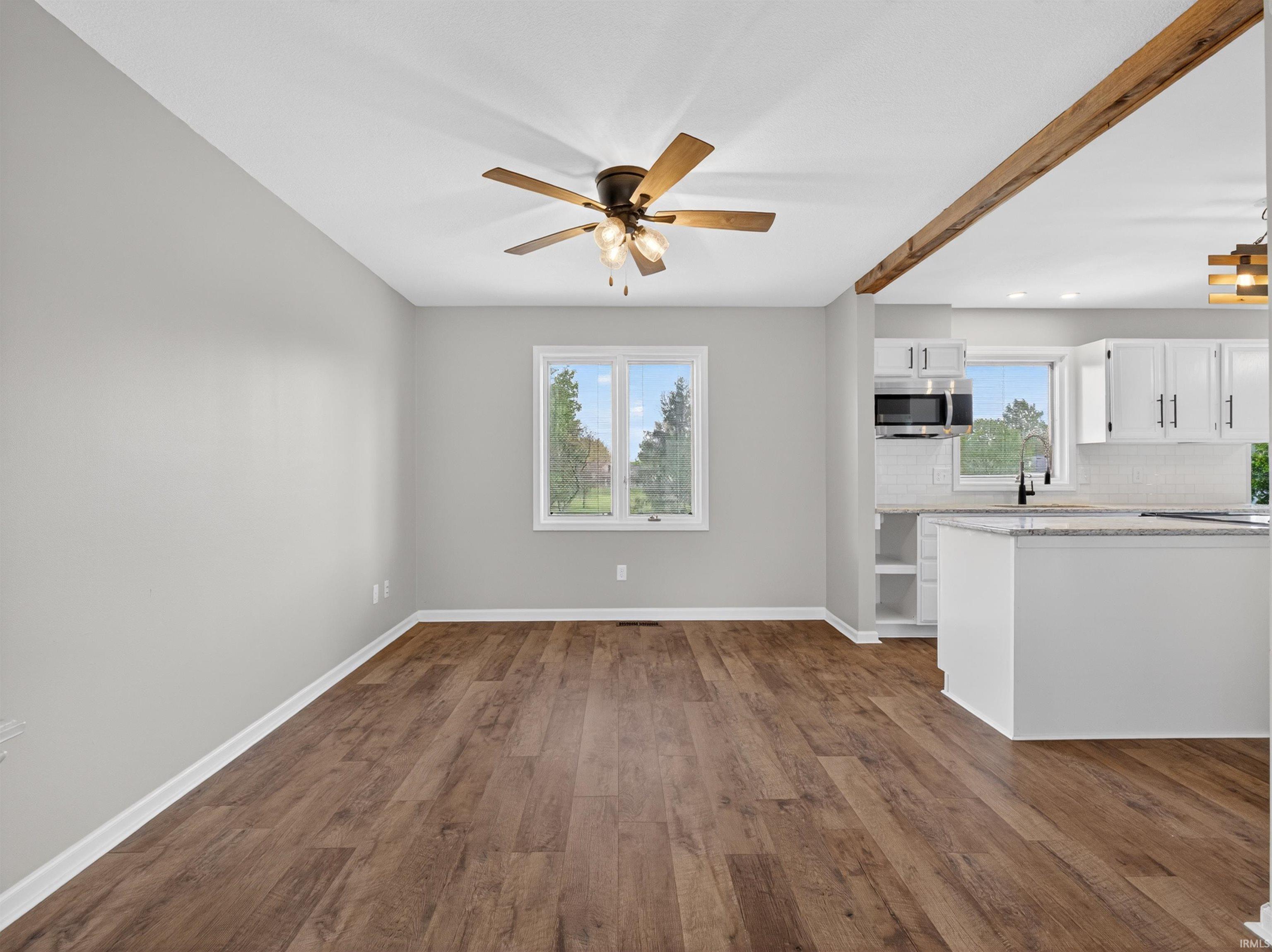 Spacious room featuring wood-finish flooring, a ceiling fan, and light gray walls
