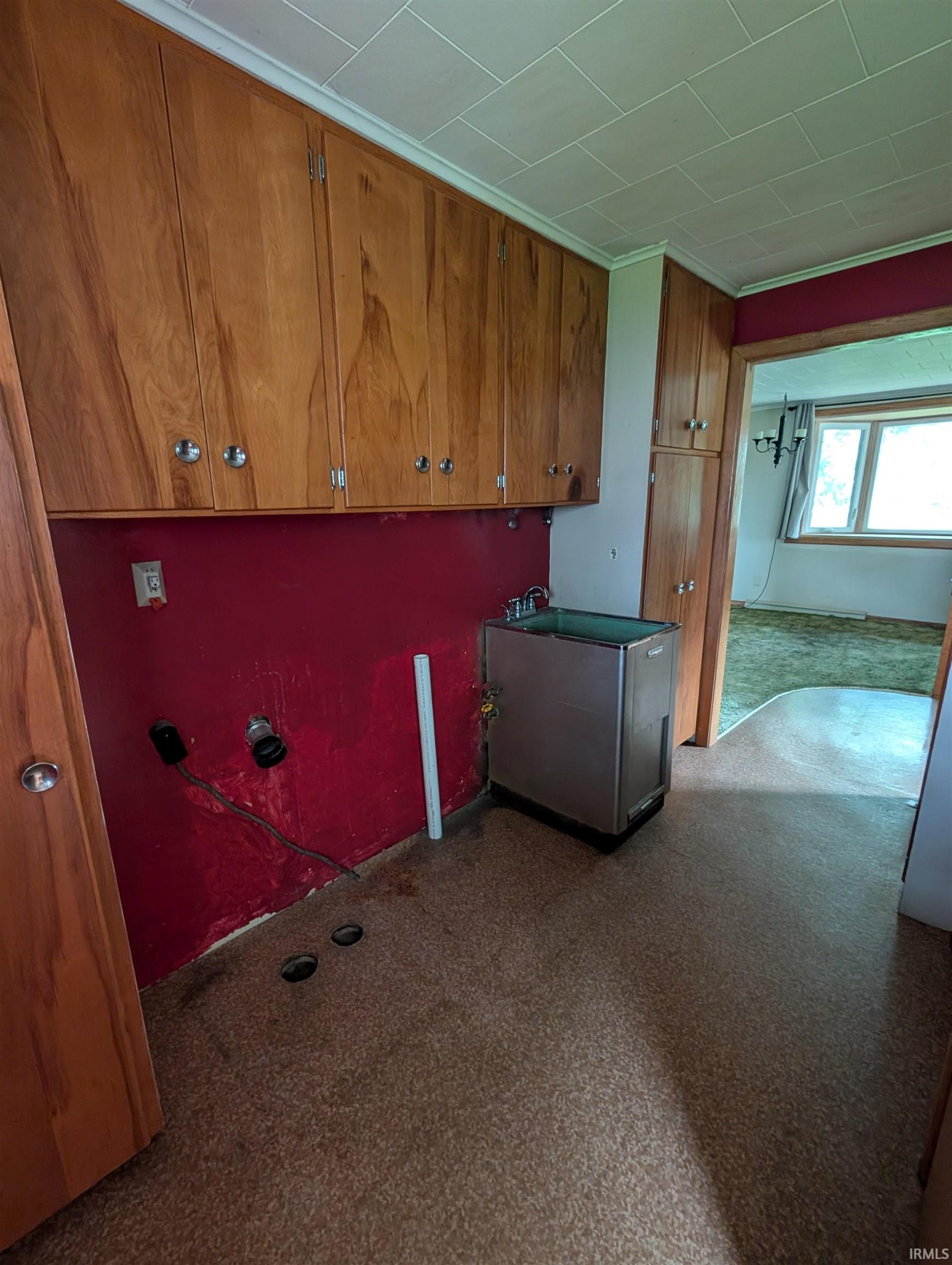 Utility area featuring extensive wood cabinetry, a built-in utility sink, and durable speckled flooring