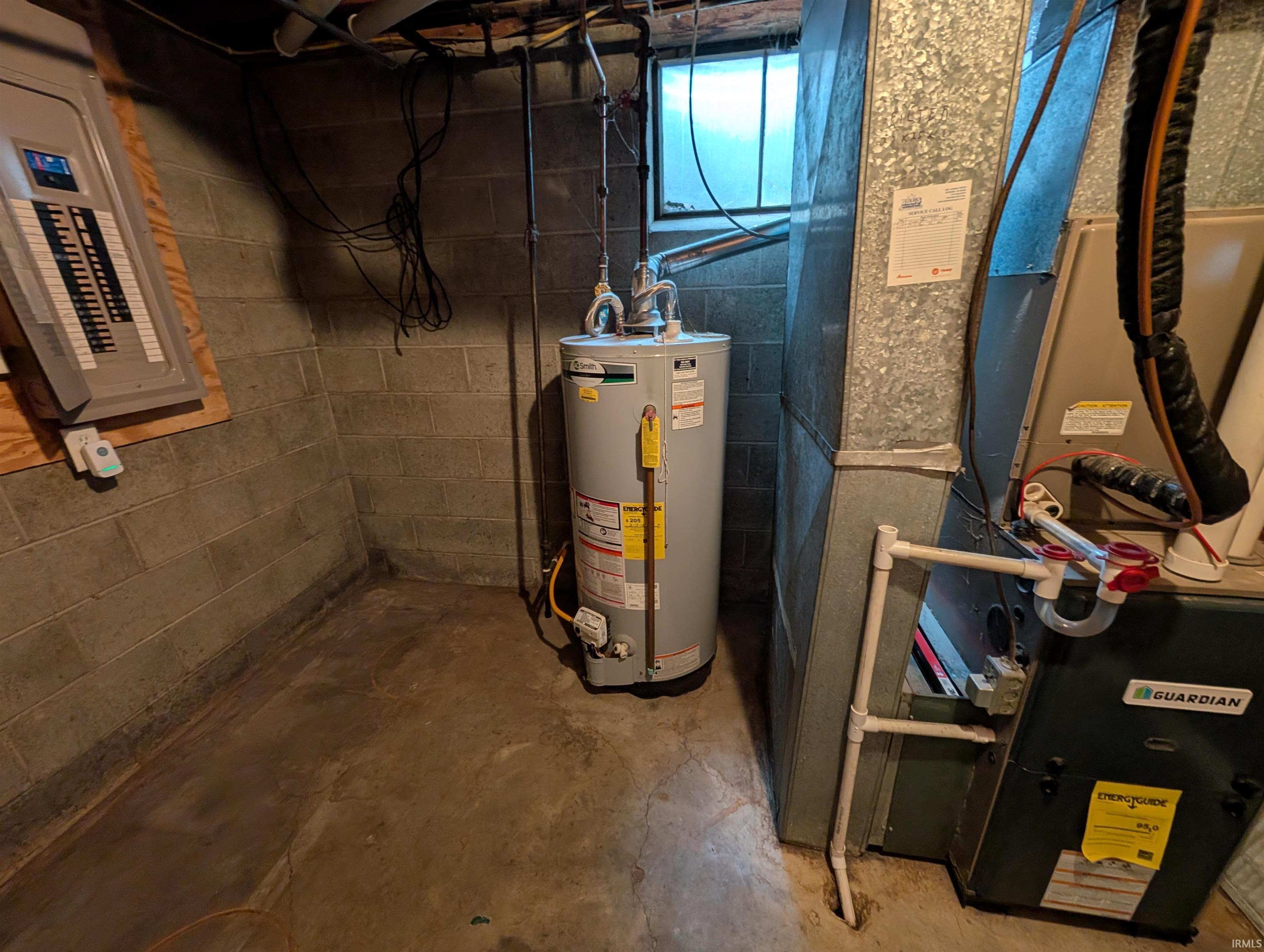 Utility area featuring a water heater, furnace, and electrical panel on a concrete block wall