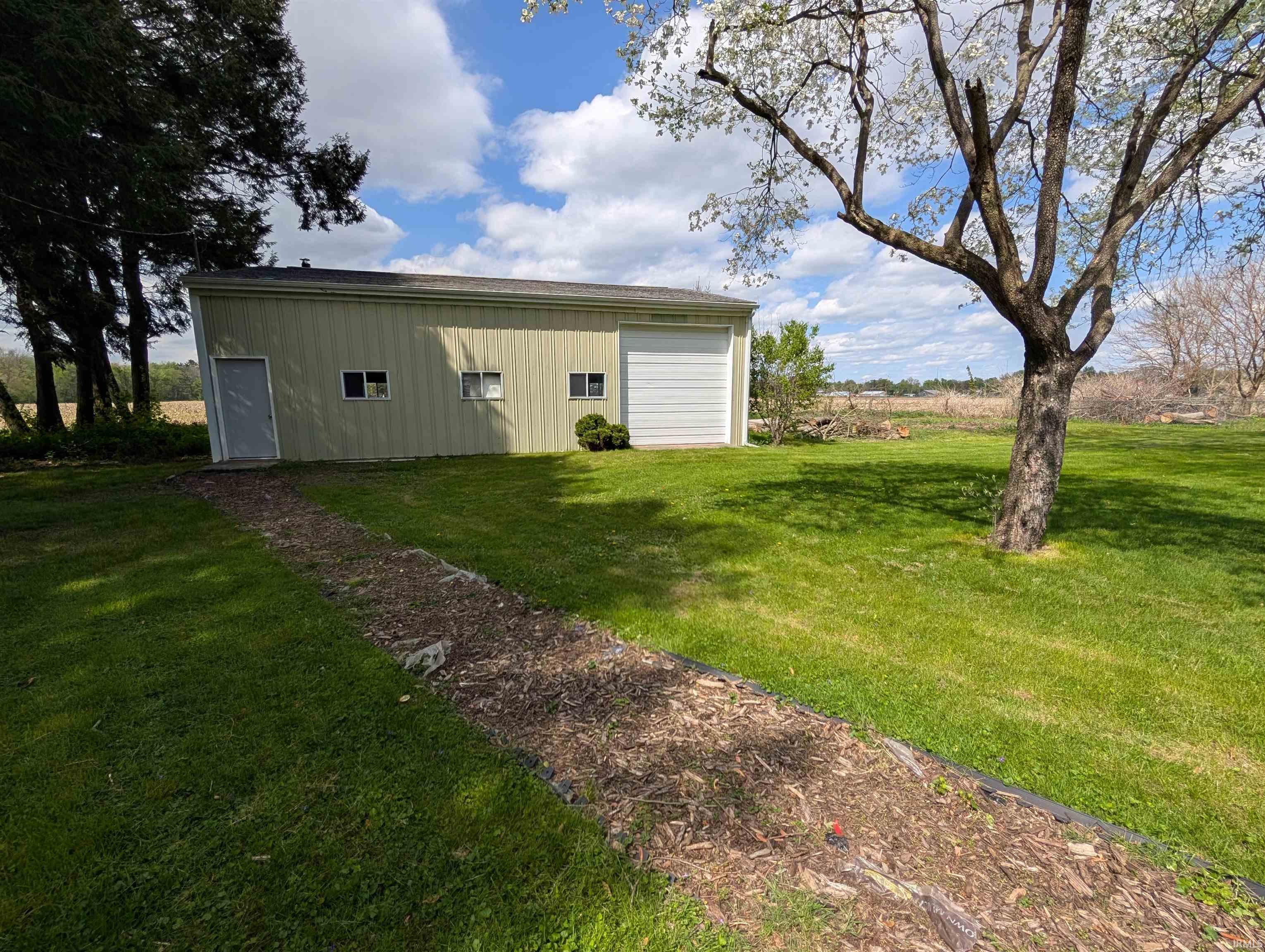 Spacious outbuilding featuring siding, multiple windows, a service door, and a roll-up garage door