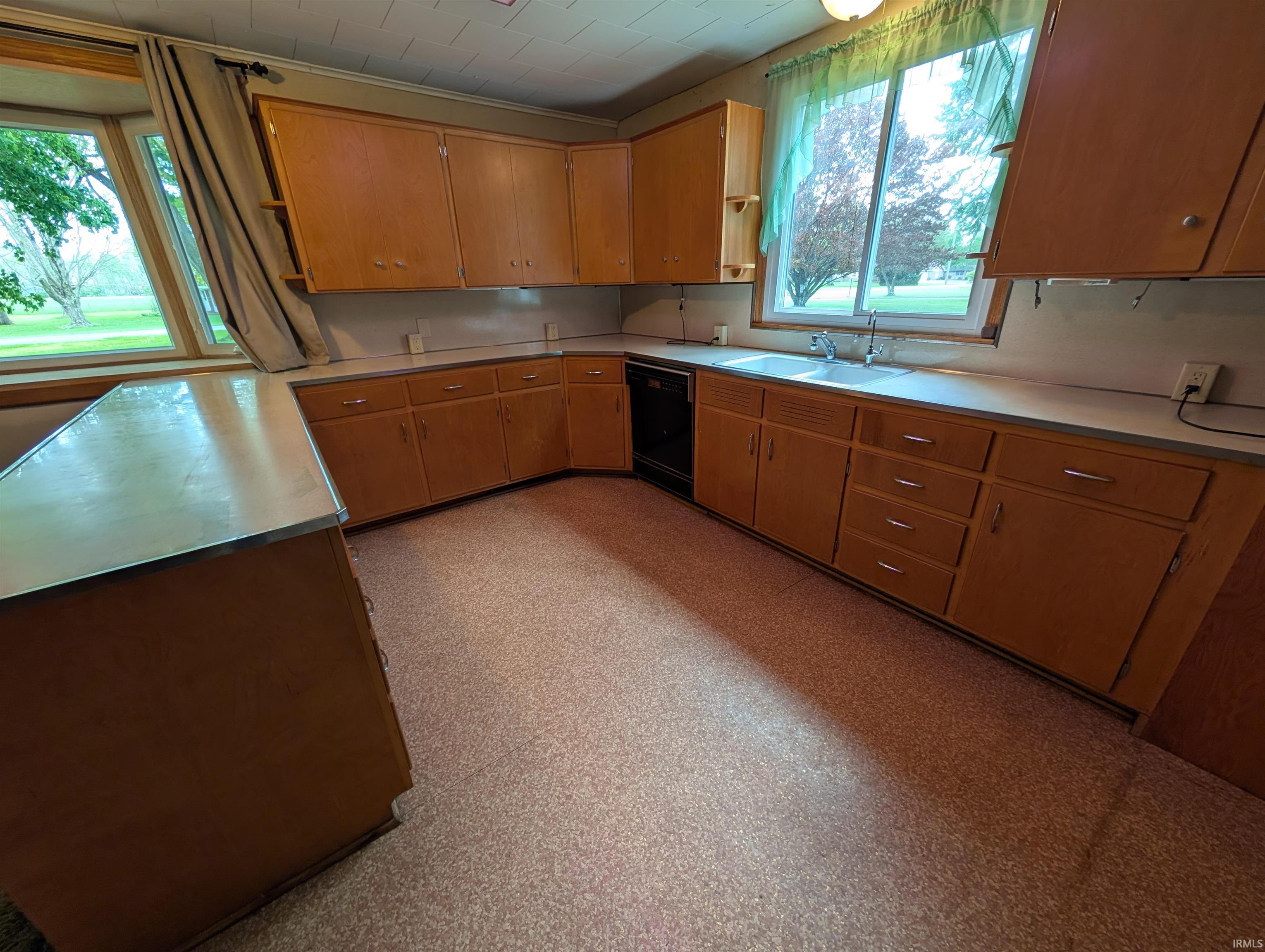 Kitchen with wood-finish cabinetry, light-toned countertops, and a double-basin sink
