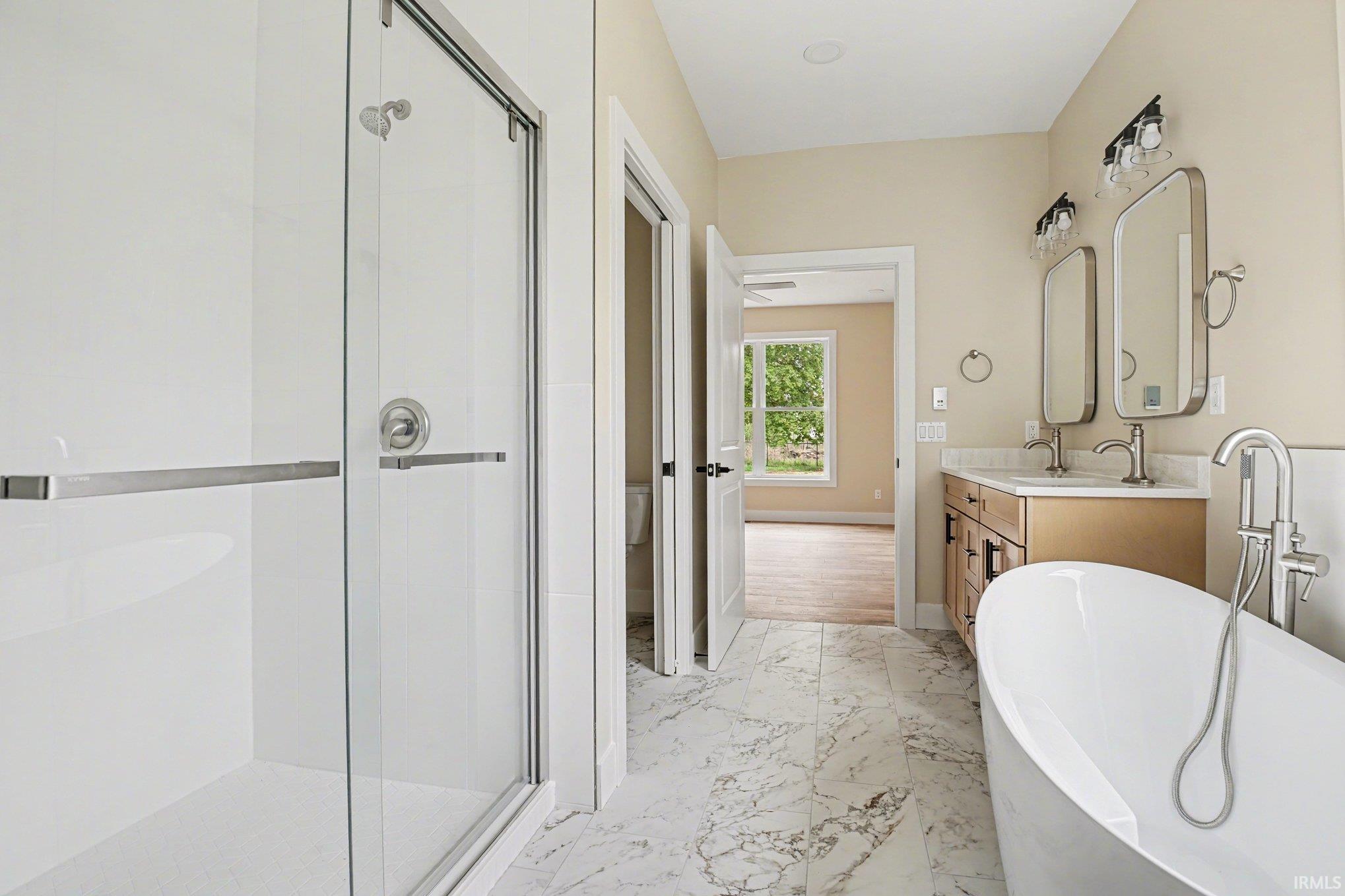 Bathroom featuring a freestanding soaking tub, dual vanity with undermount sinks, and a walk-in shower with clear glass enclosure