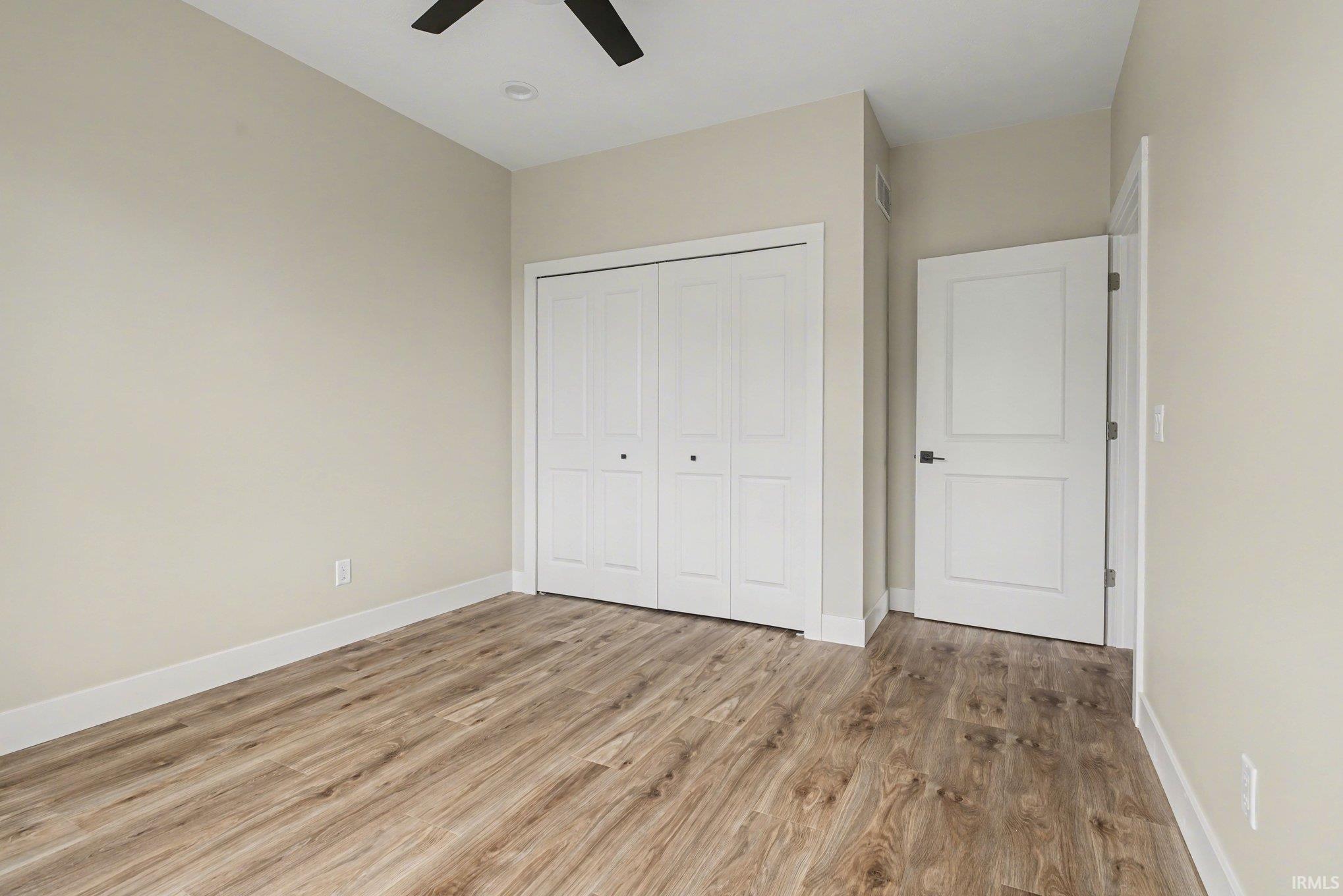 Neutral-toned room with wood-finish flooring, a ceiling fan, and recessed lighting
