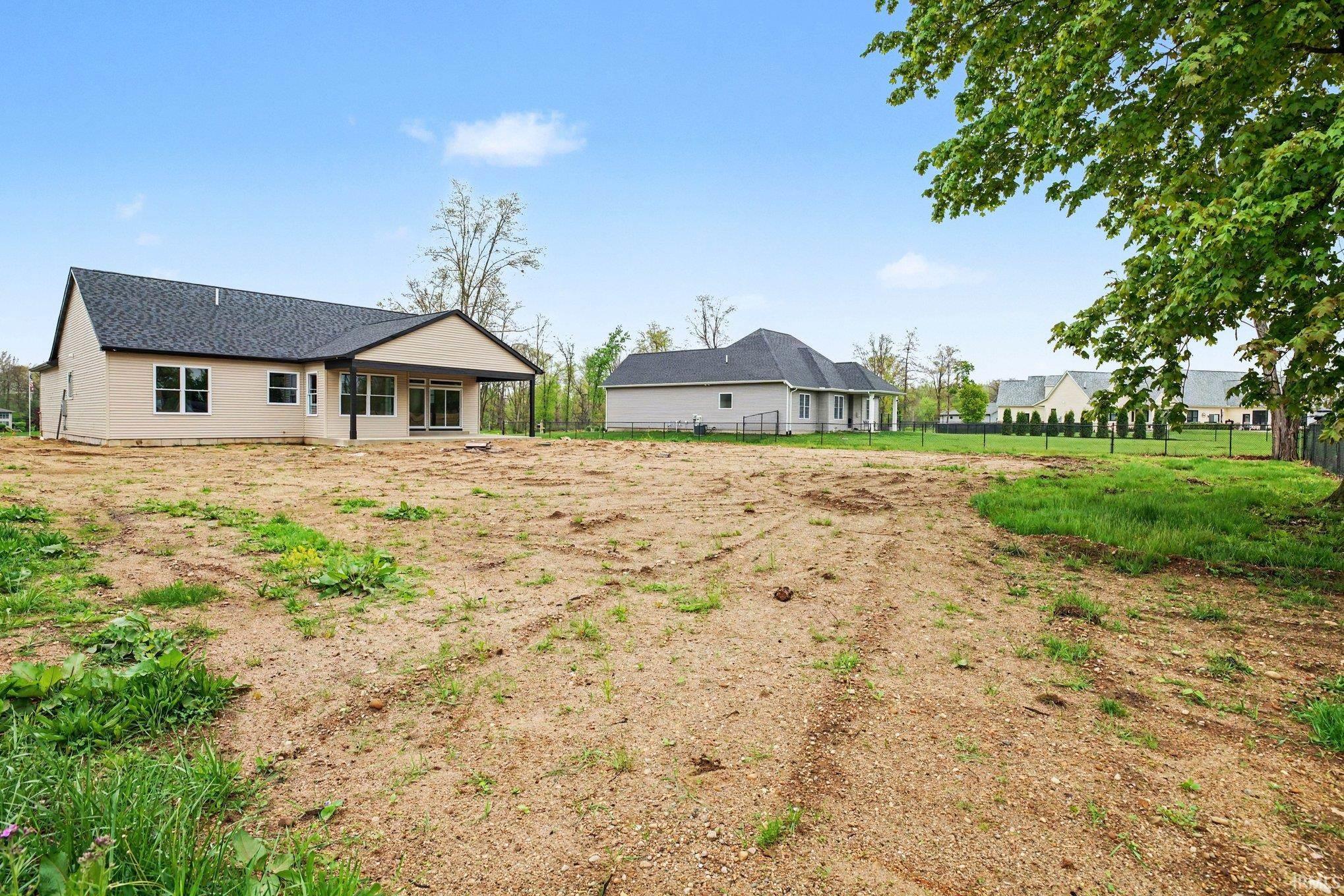 Contemporary ranch-style residence featuring light-colored siding, a dark shingle roof, and multiple rear windows