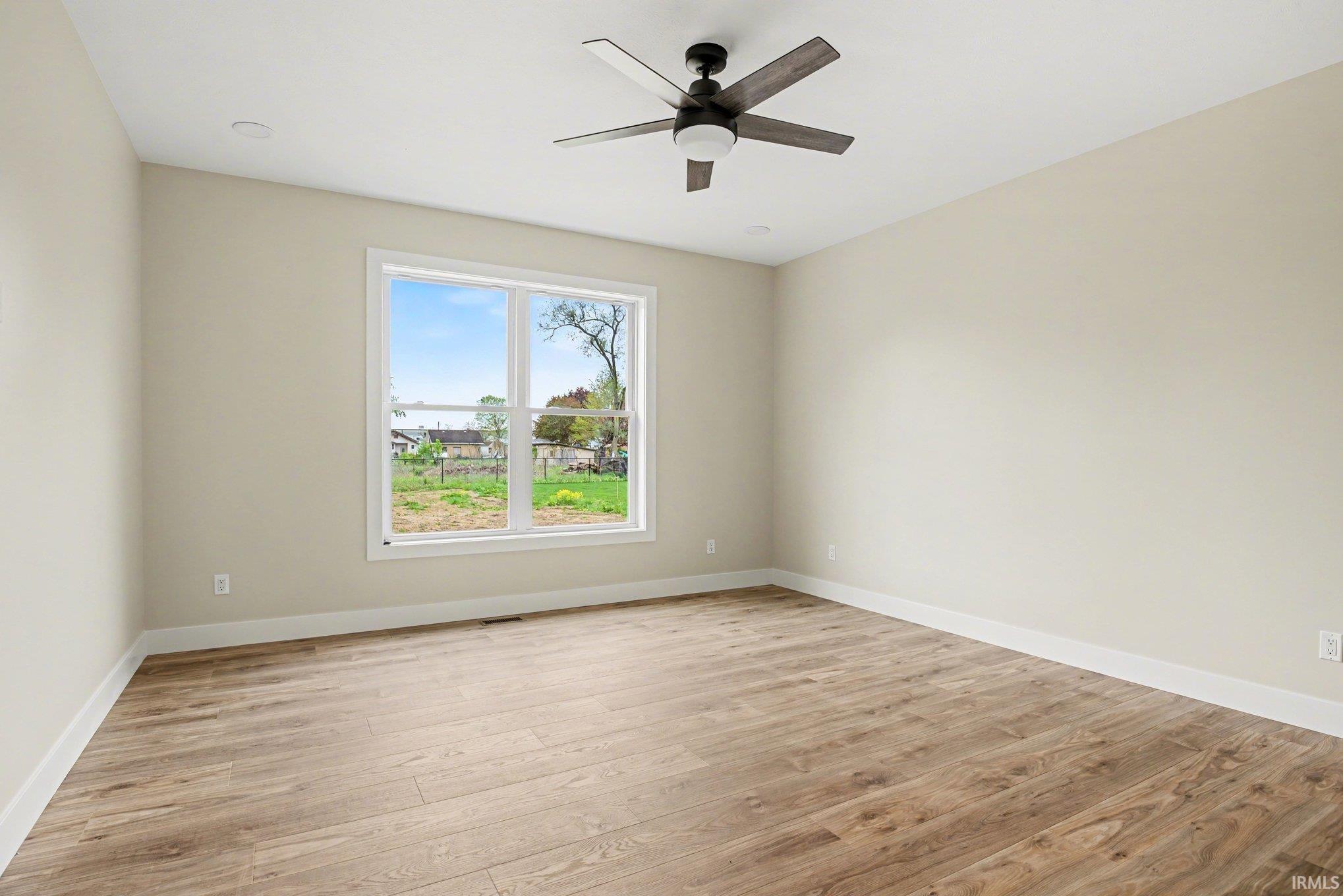 Bright room featuring a large window, wood-finish flooring, white baseboards, a ceiling fan with light, and recessed lighting