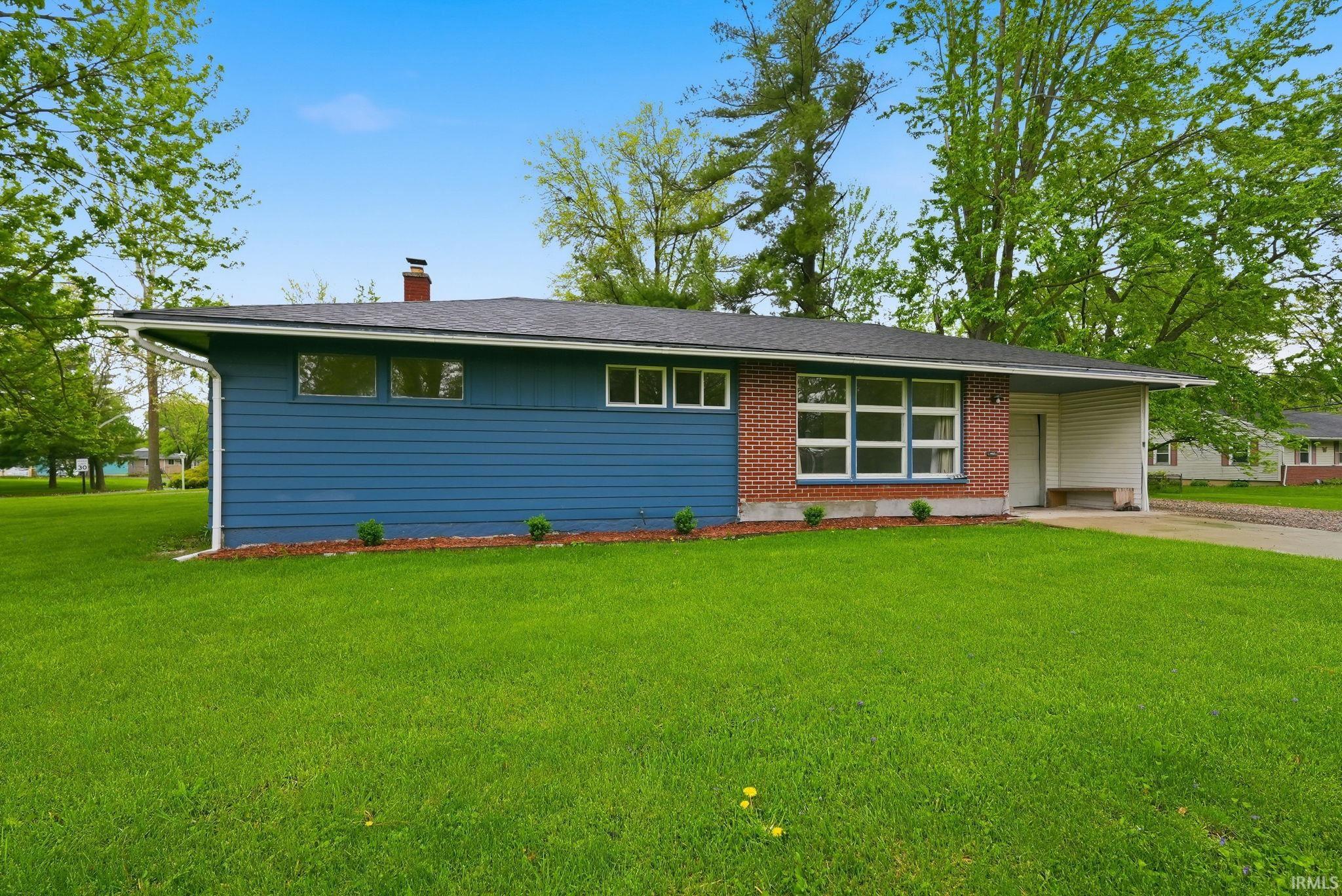 Ranch-style exterior featuring blue horizontal siding and red brick accents