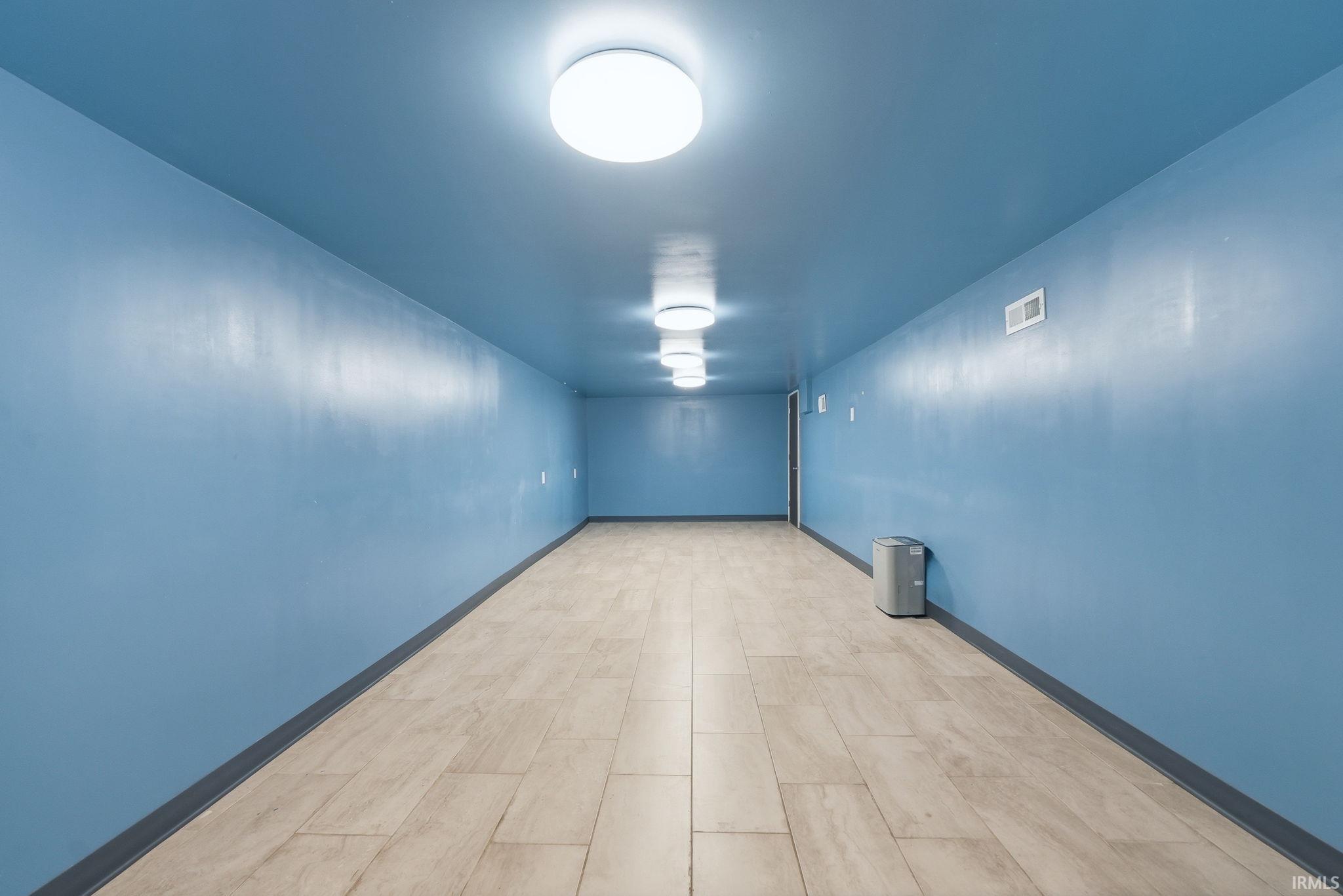 Corridor featuring light blue painted walls and ceiling, recessed ceiling lights, and light-toned tile flooring