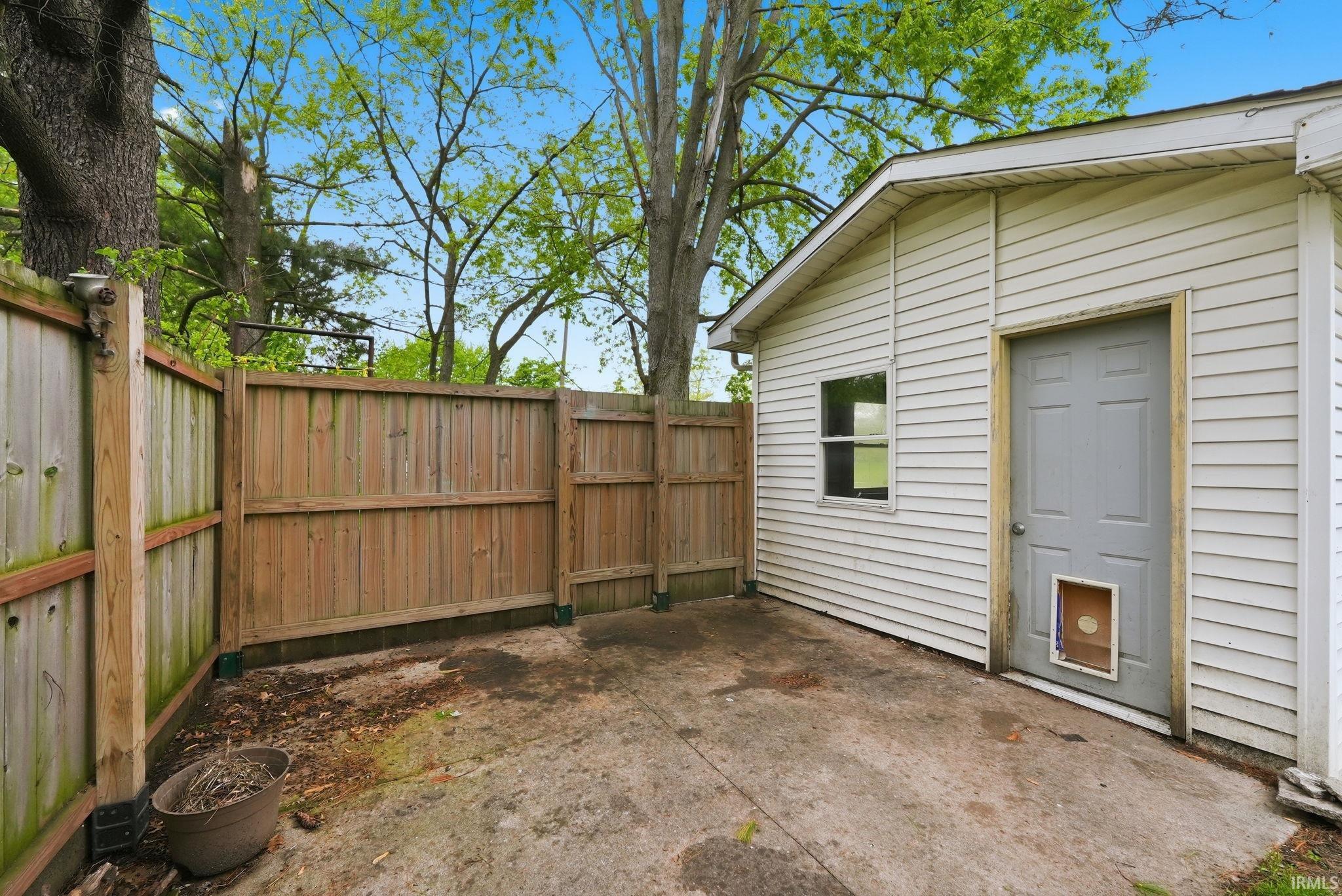 Concrete patio with wood privacy fence and vinyl-sided exterior building