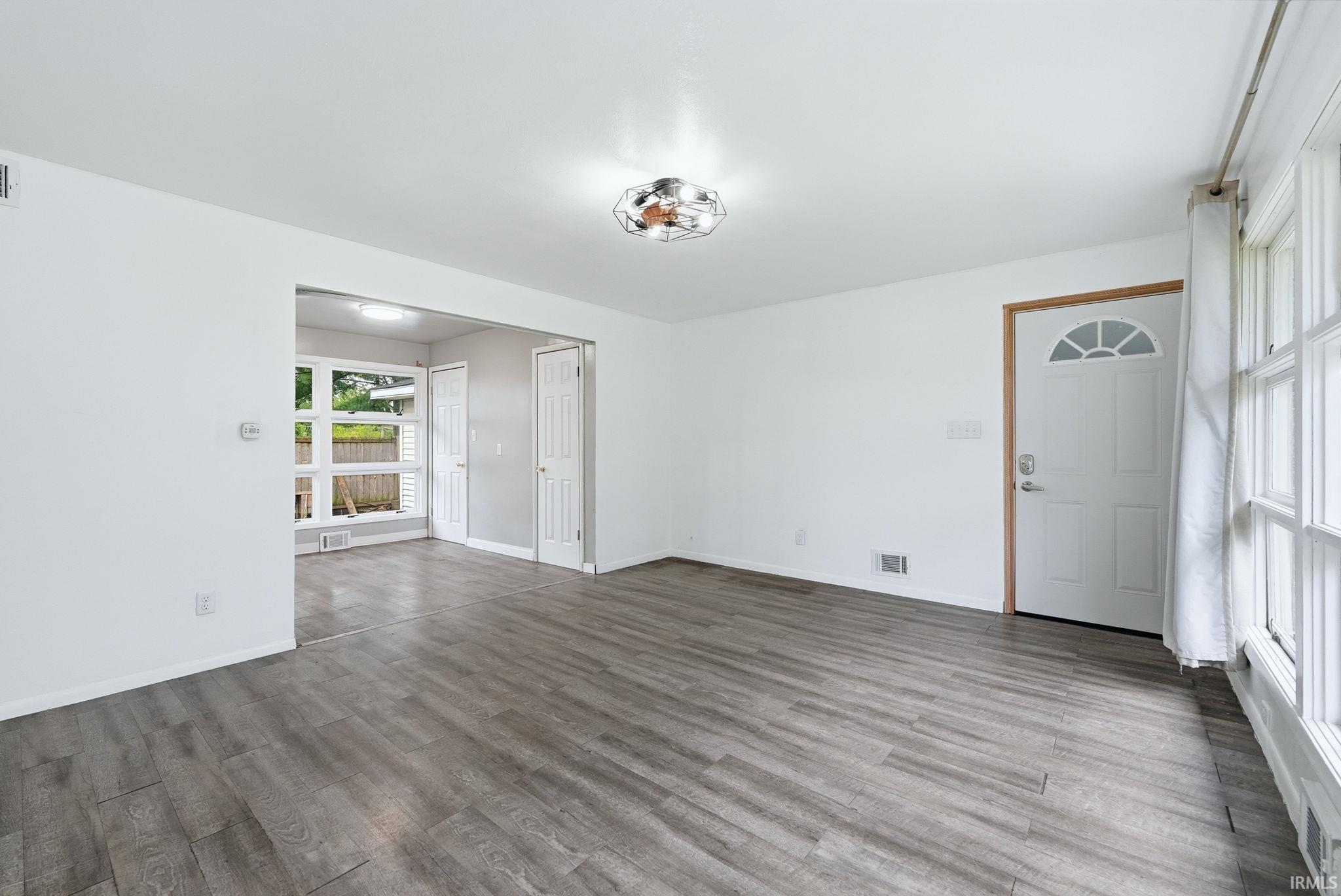 Bright living space featuring wood-finish flooring, white walls, and a contemporary ceiling fixture