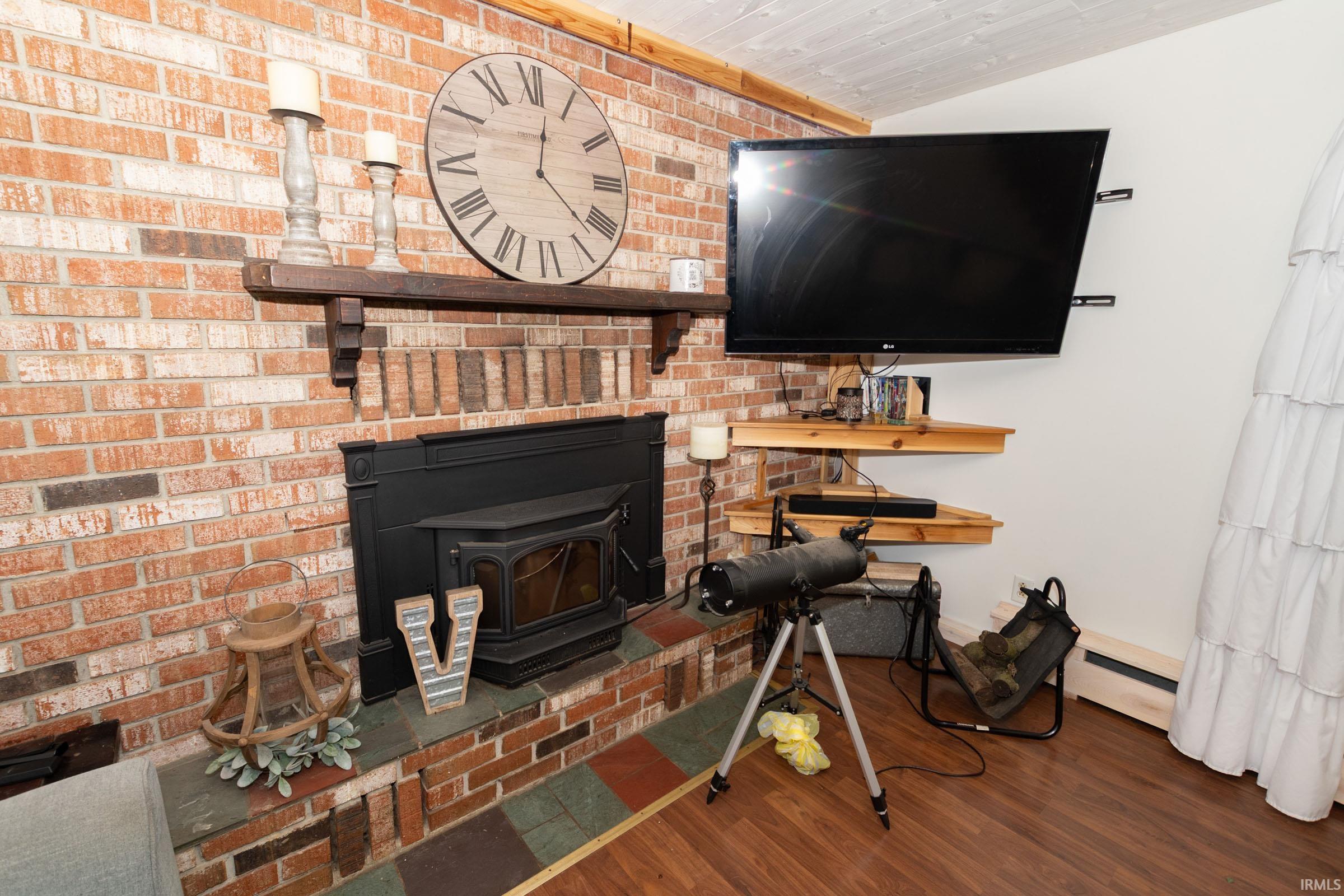 Brick fireplace featuring a cast-iron wood stove insert, a wood mantel, and a tiled hearth