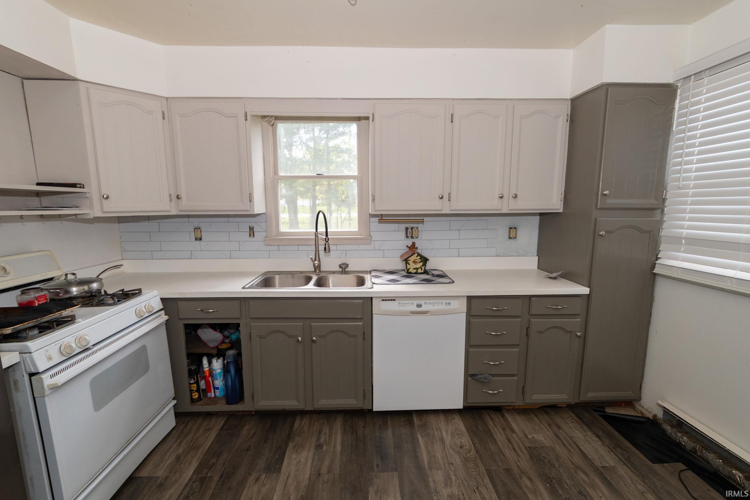 Kitchen featuring wood-finish flooring, two-tone cabinetry, white countertops, and a subway tile backsplash