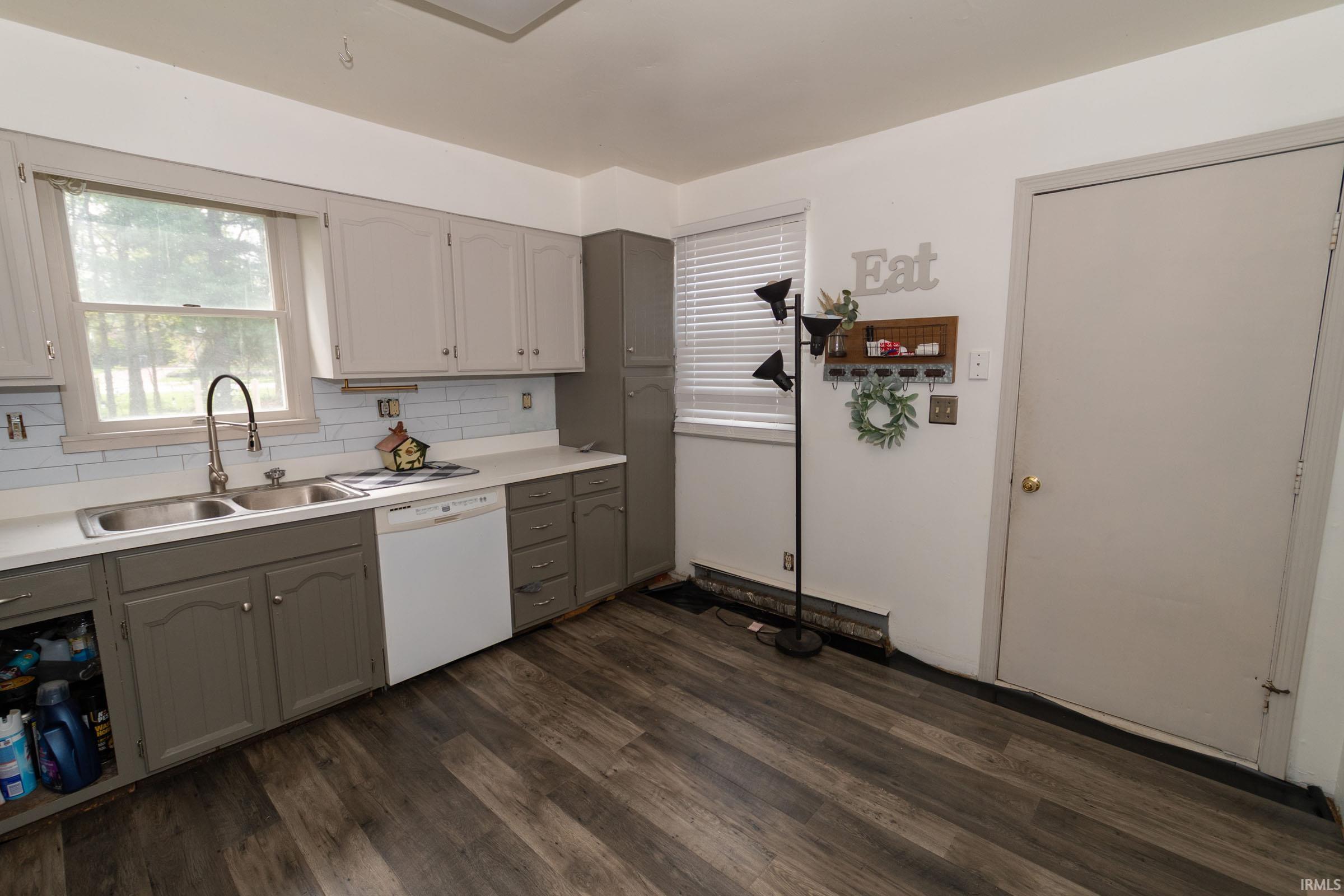 Kitchen with wood-finish flooring, two-tone cabinetry, light countertop, and a double basin sink with a gooseneck faucet