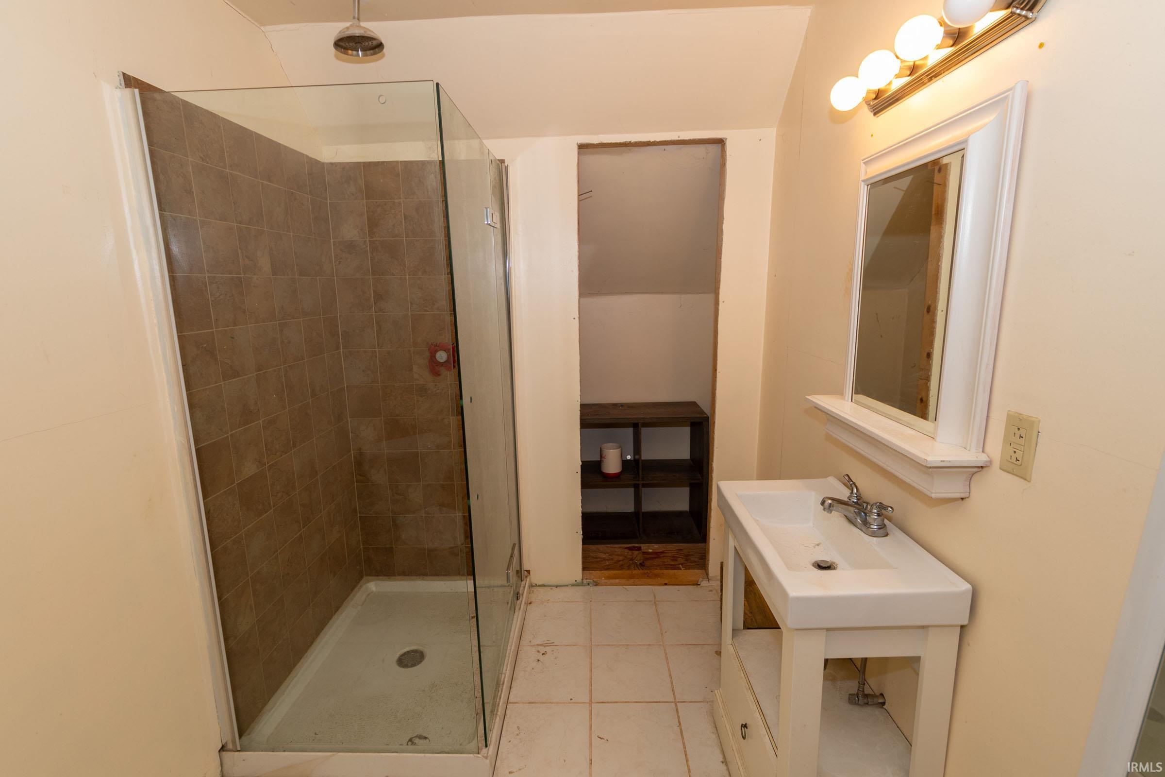 Shower stall with glass enclosure and neutral-toned wall tiling