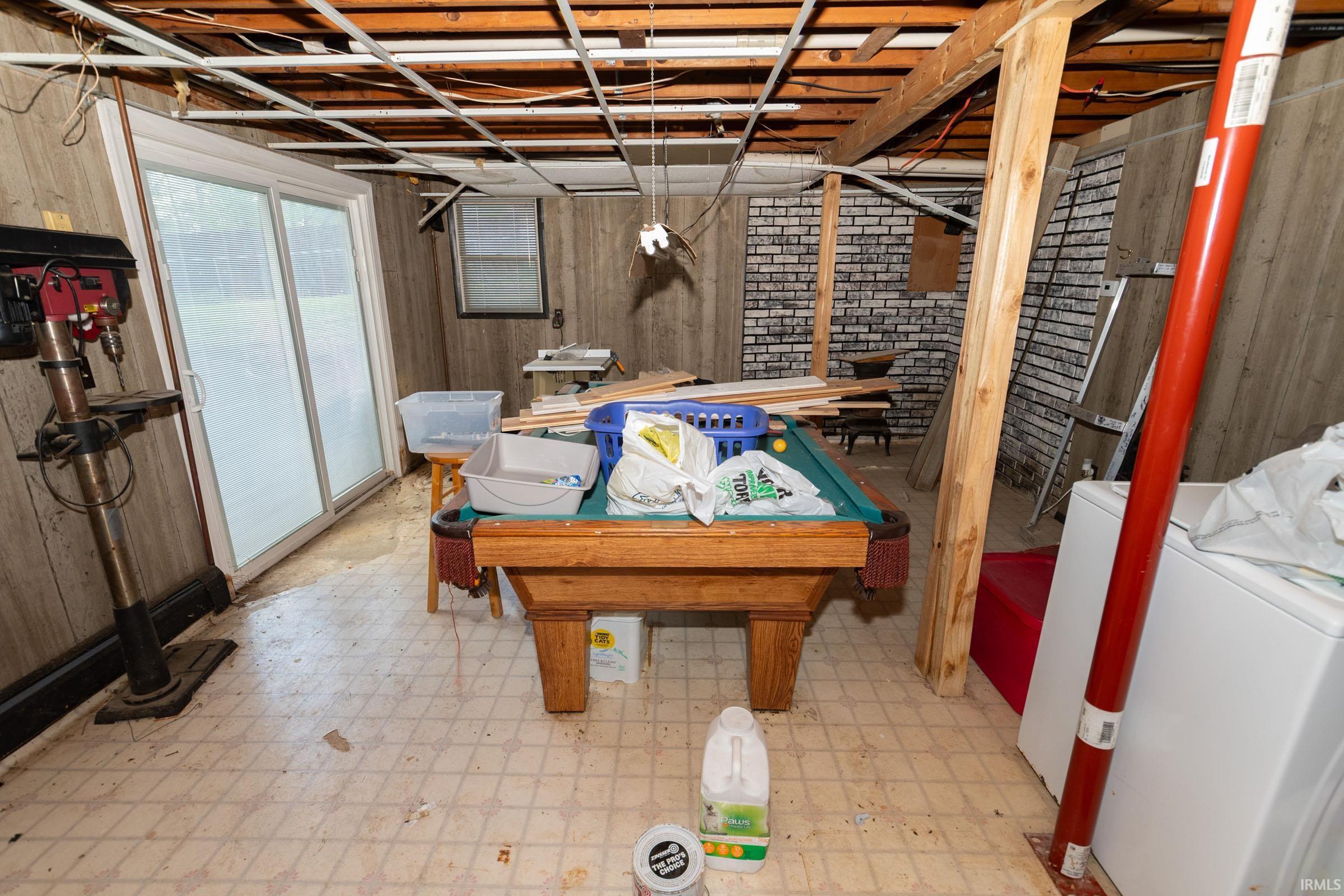 Basement space featuring patterned linoleum flooring and wood paneling, with exposed ceiling joists