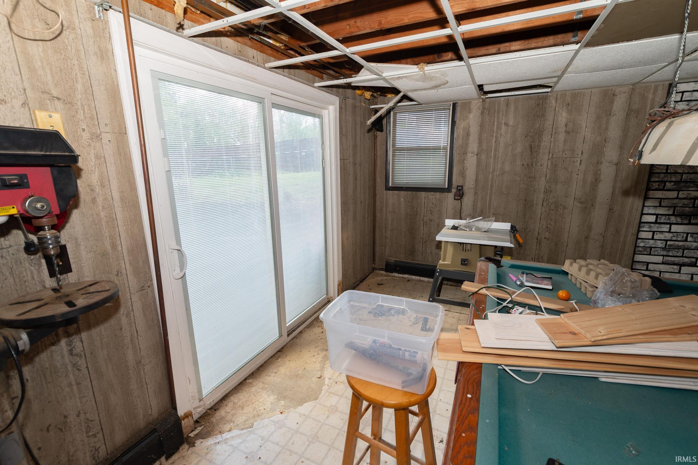Sliding glass door entry with wood-paneled walls and a drop ceiling