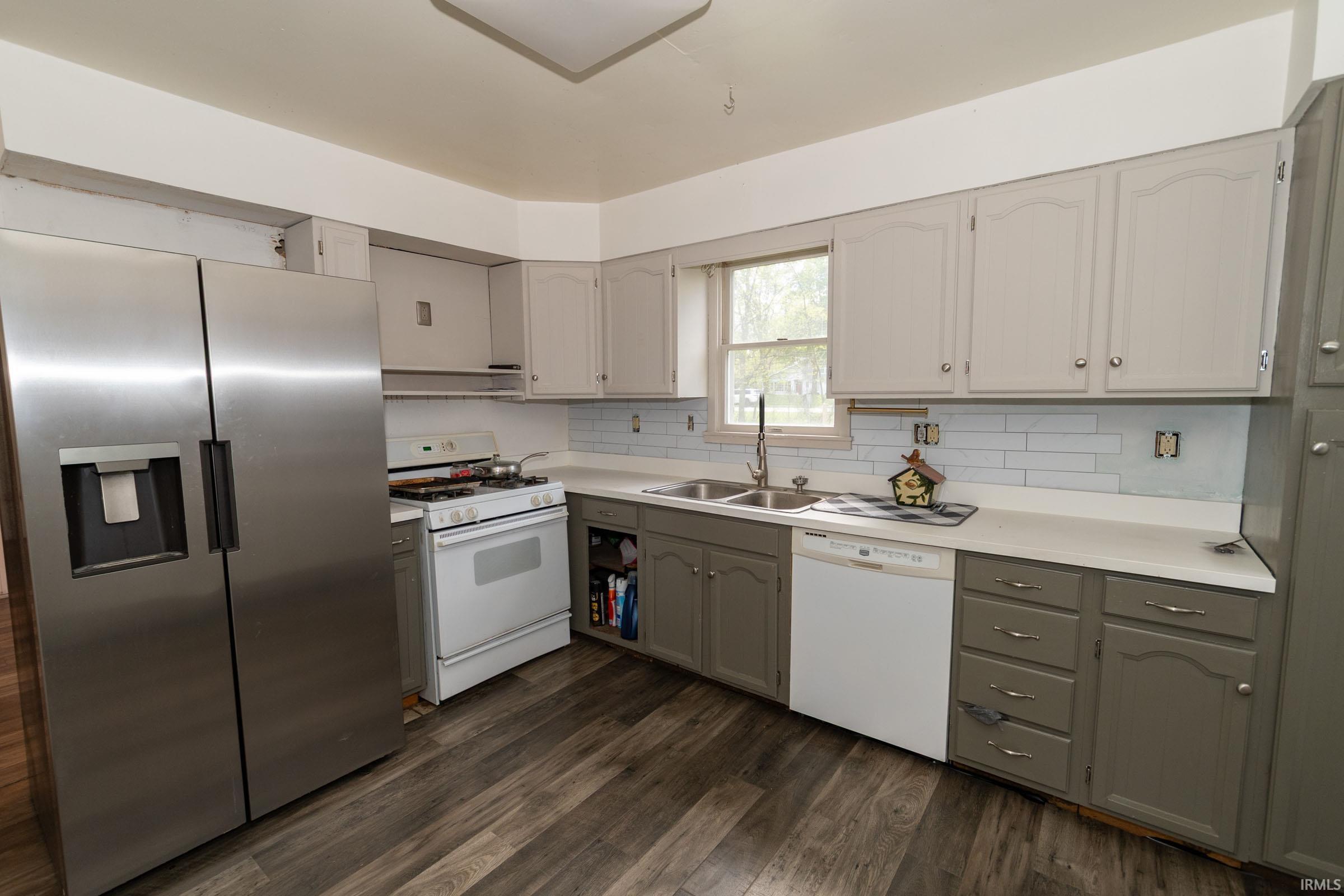 Kitchen featuring wood-finish flooring, two-tone cabinetry, white countertops, and a subway tile backsplash