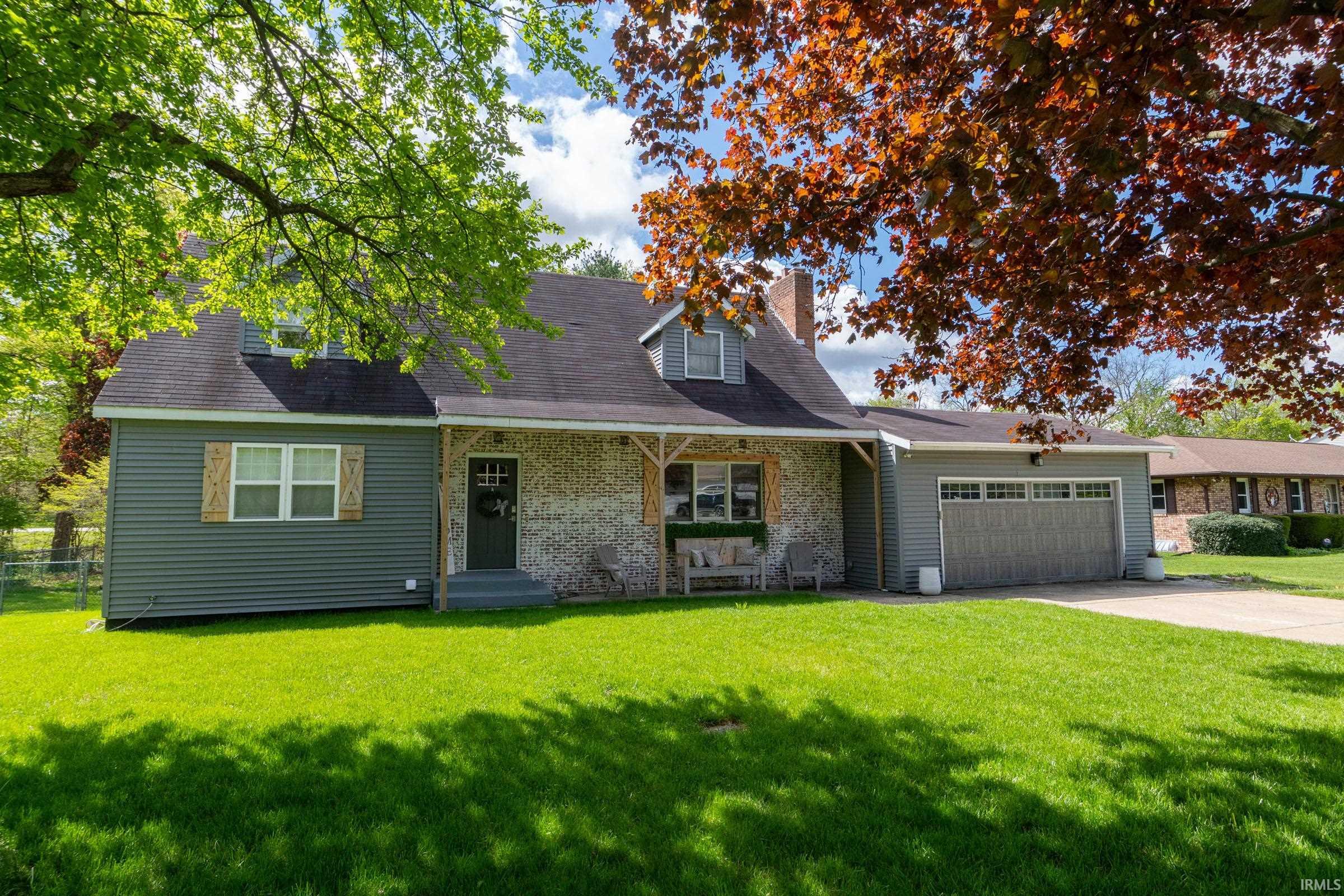 Exterior featuring a stone and siding facade, covered entry porch, dark gray front door, and an attached garage with a drive
