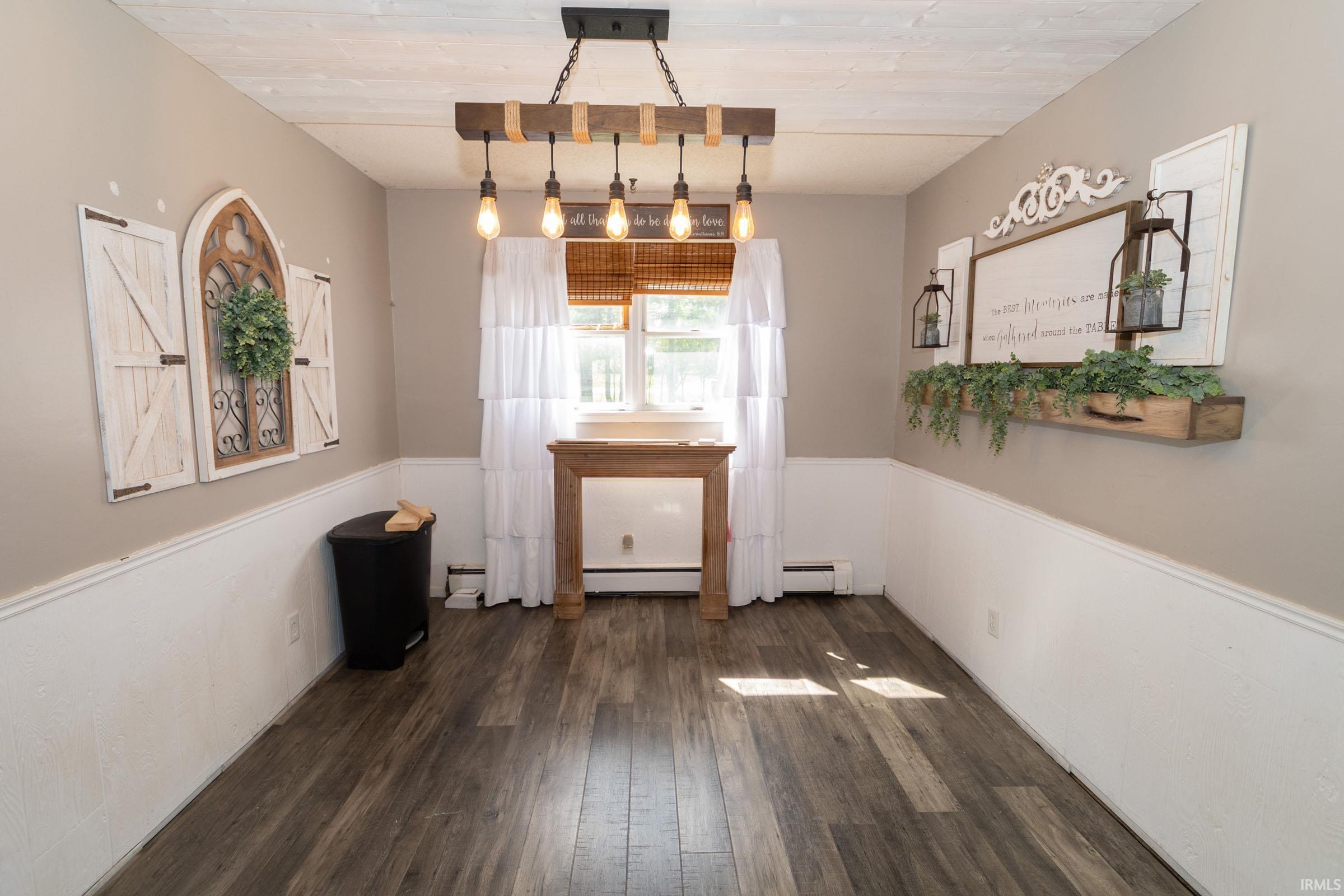 Spacious room featuring wood-finish flooring and a central chandelier with exposed Edison bulbs