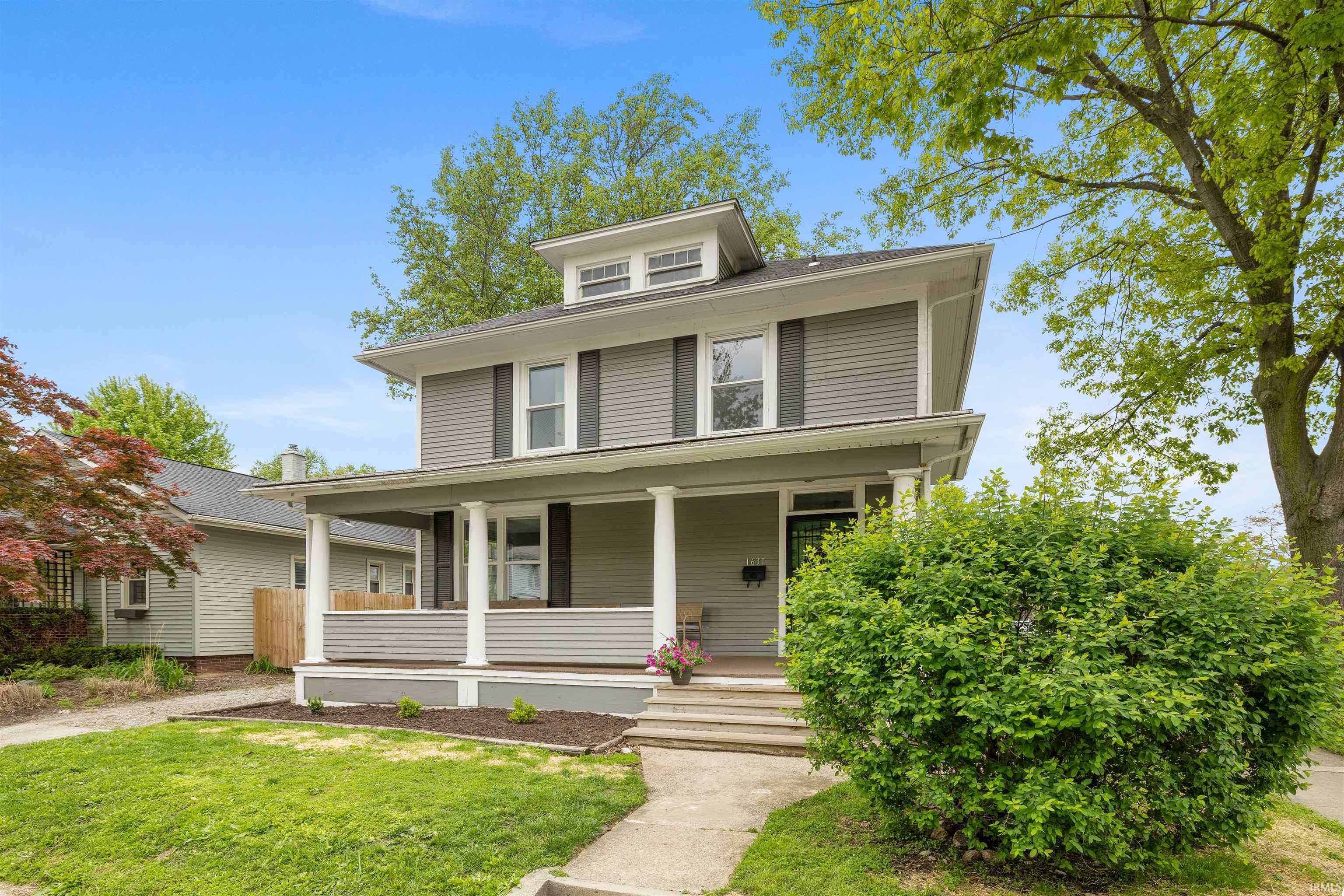 Craftsman-style home featuring gray horizontal siding and a full-width covered front porch with white columns