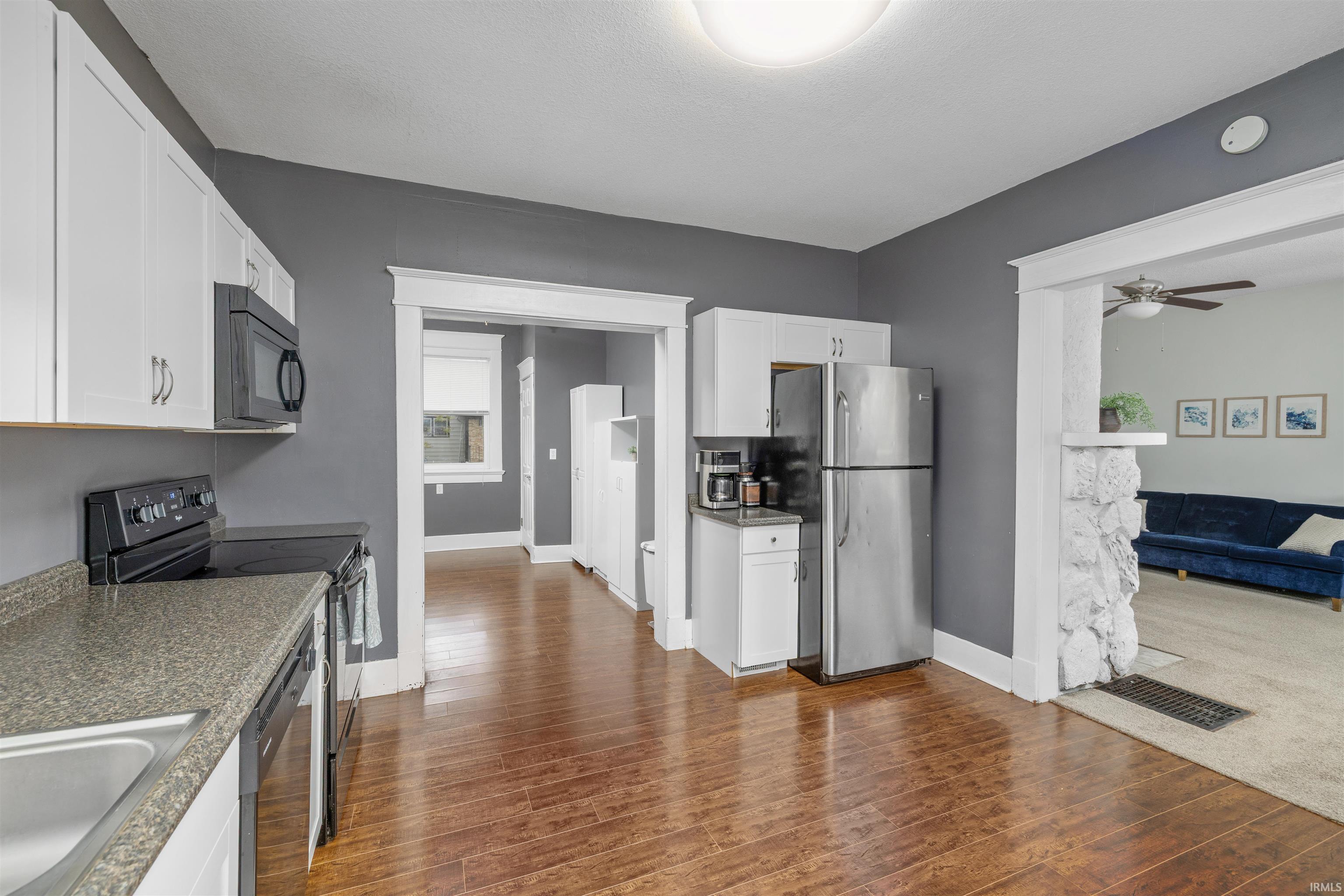 Kitchen featuring wood-finish flooring, white cabinetry, dark countertops, and stainless steel appliances