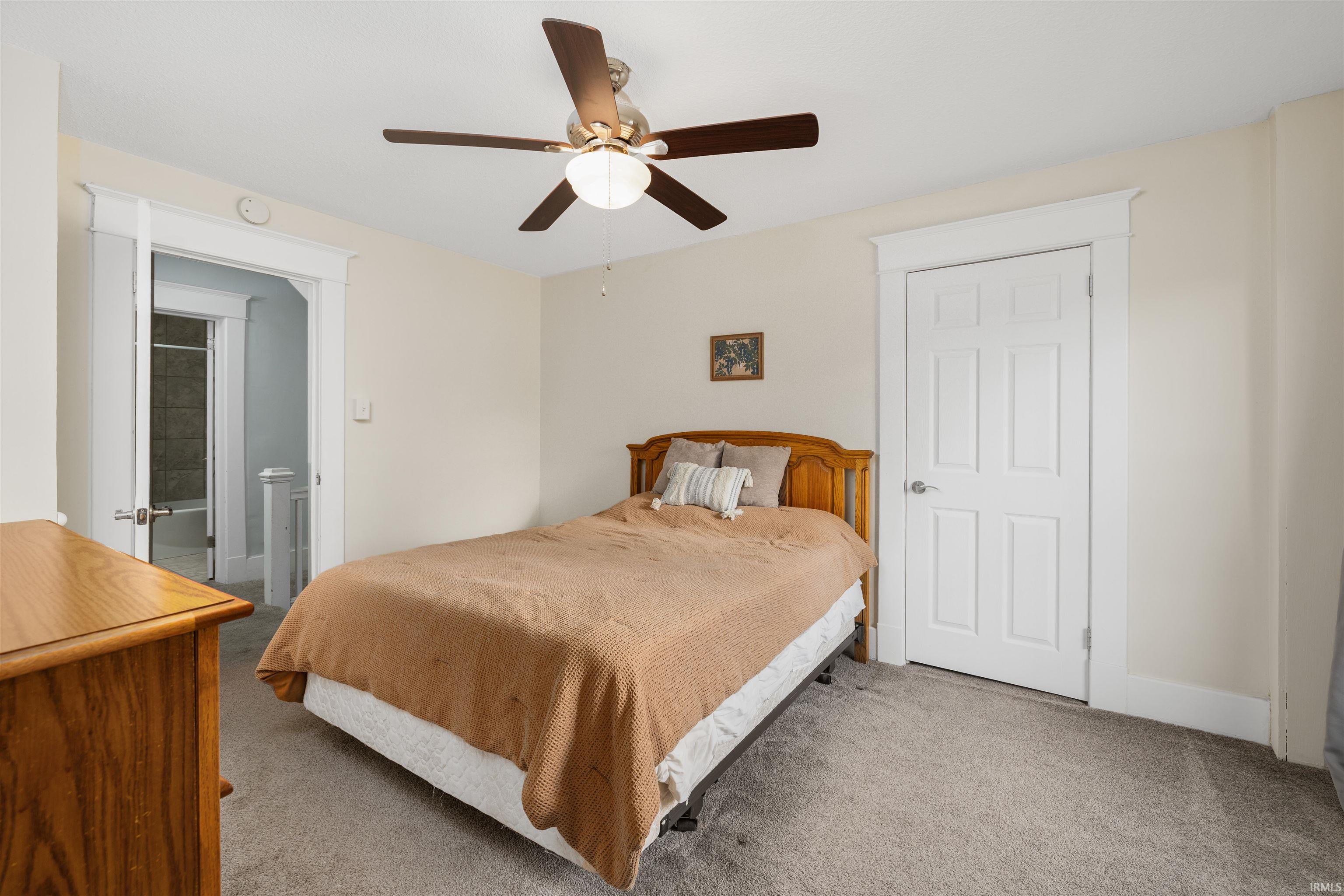Carpeted room featuring a ceiling fan with integrated lighting, a white six-panel door, and white trimwork