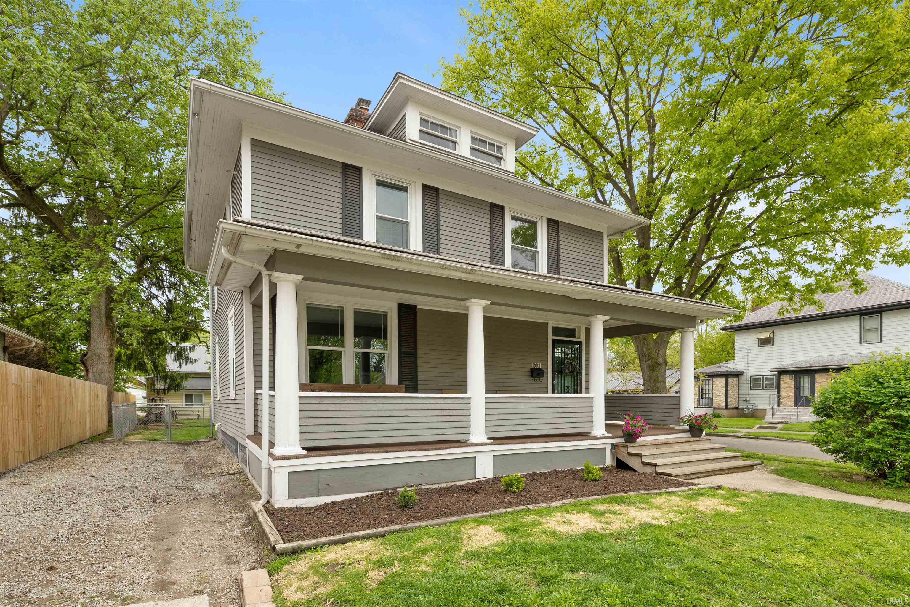 Two-story residence featuring horizontal siding, a covered porch with white columns, and a dormer window