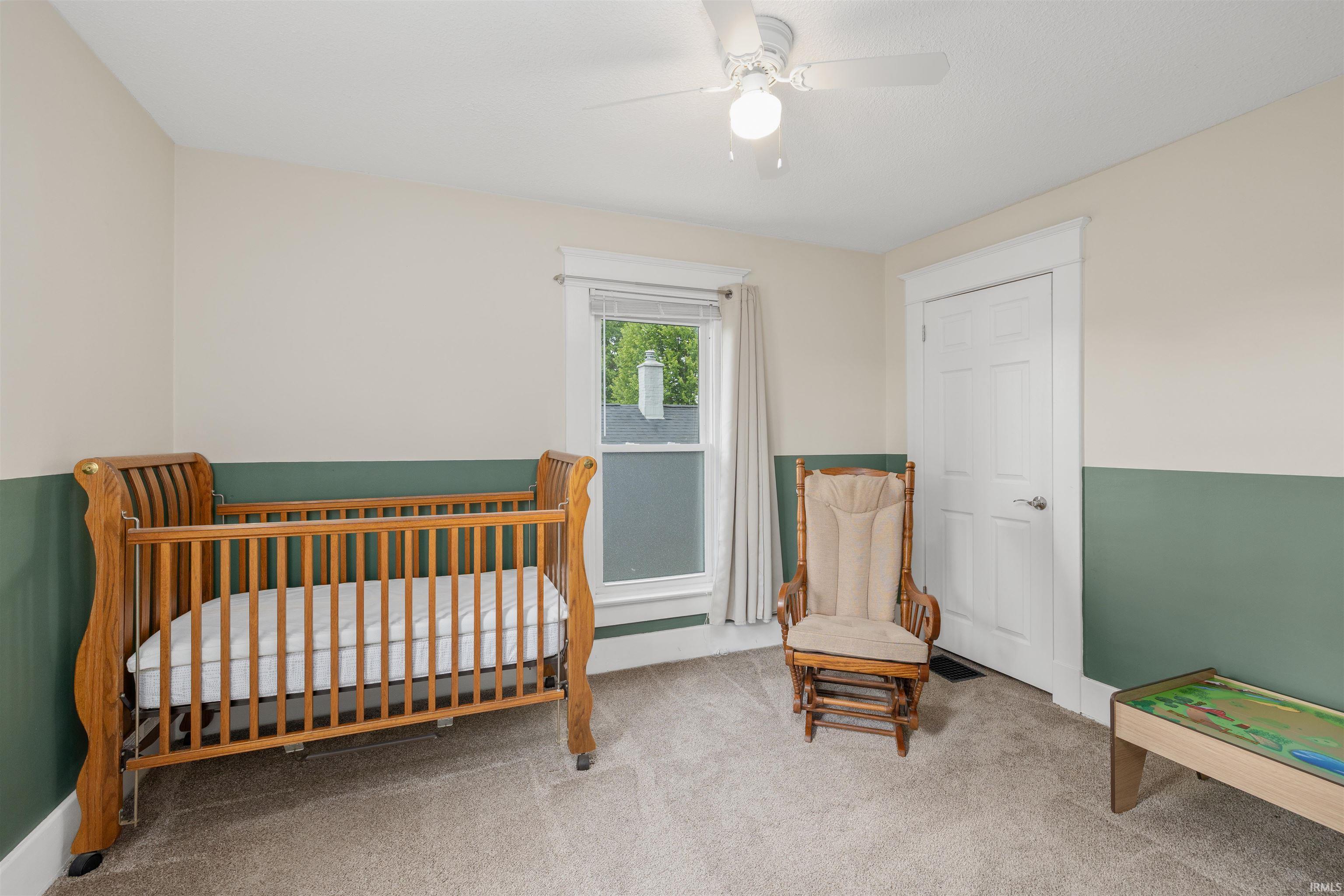 Carpeted room featuring a ceiling fan, a window with exterior views, and a paneled door