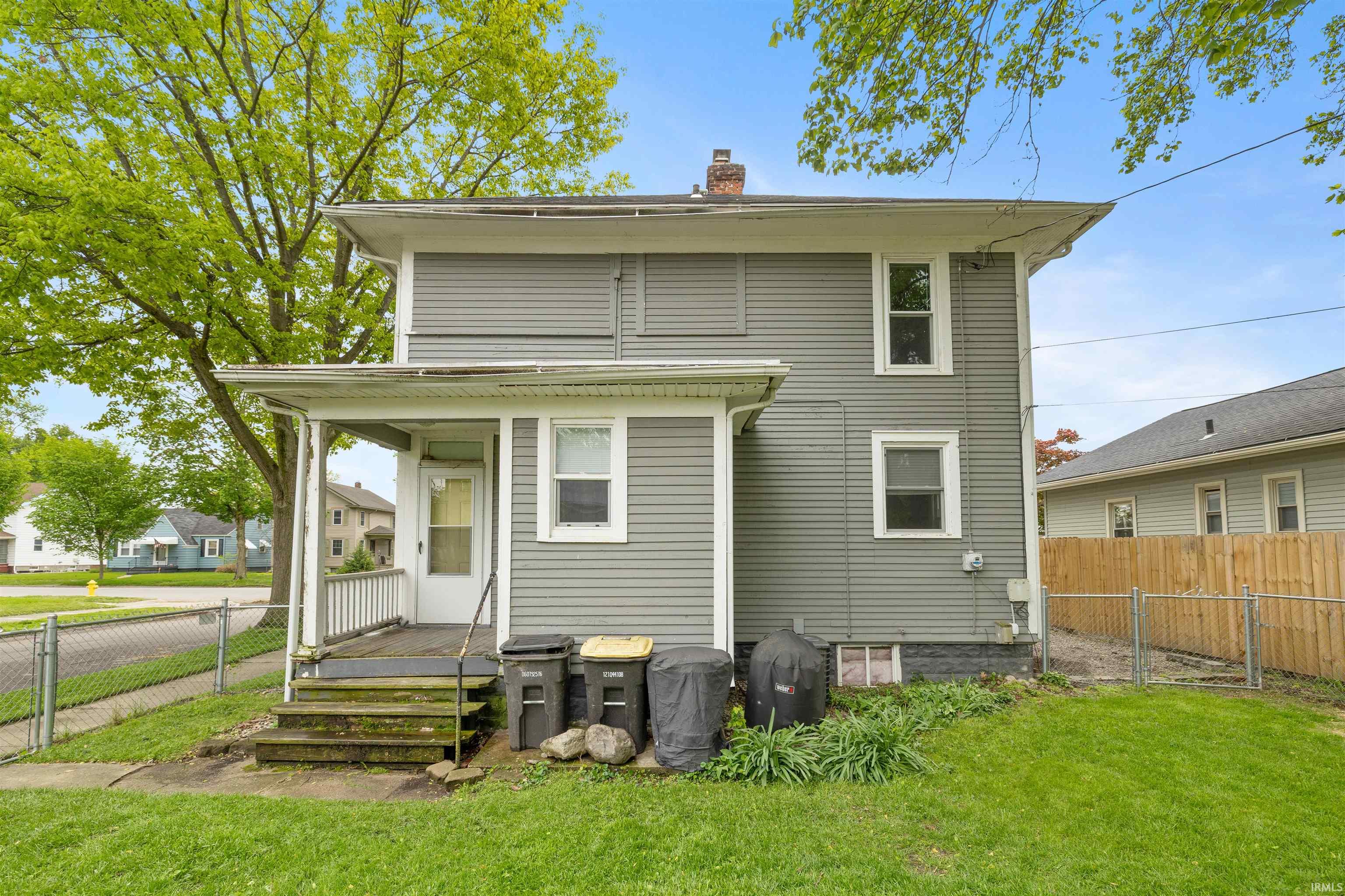 Rear exterior featuring gray siding and a covered porch with white railing