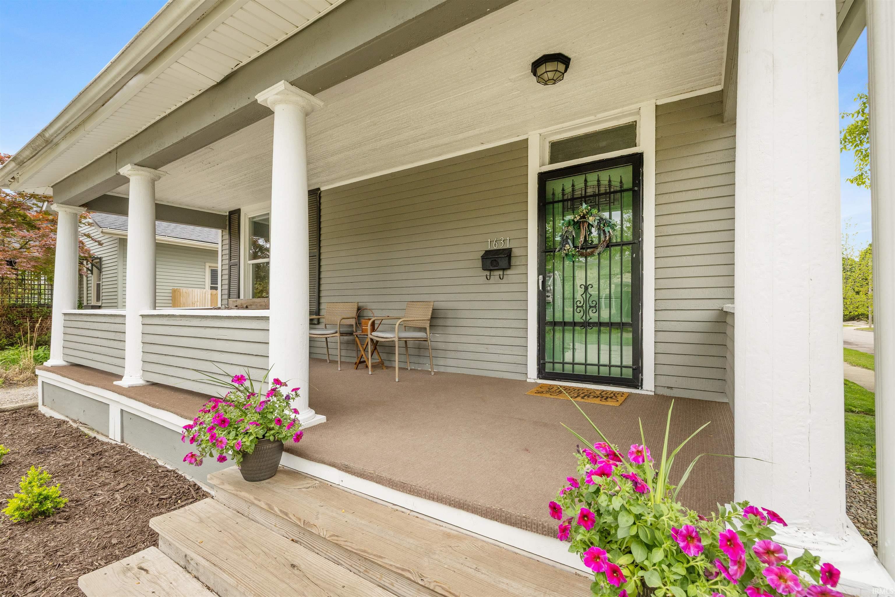 Expansive covered porch featuring a carpeted surface, four substantial white columns, and horizontal siding