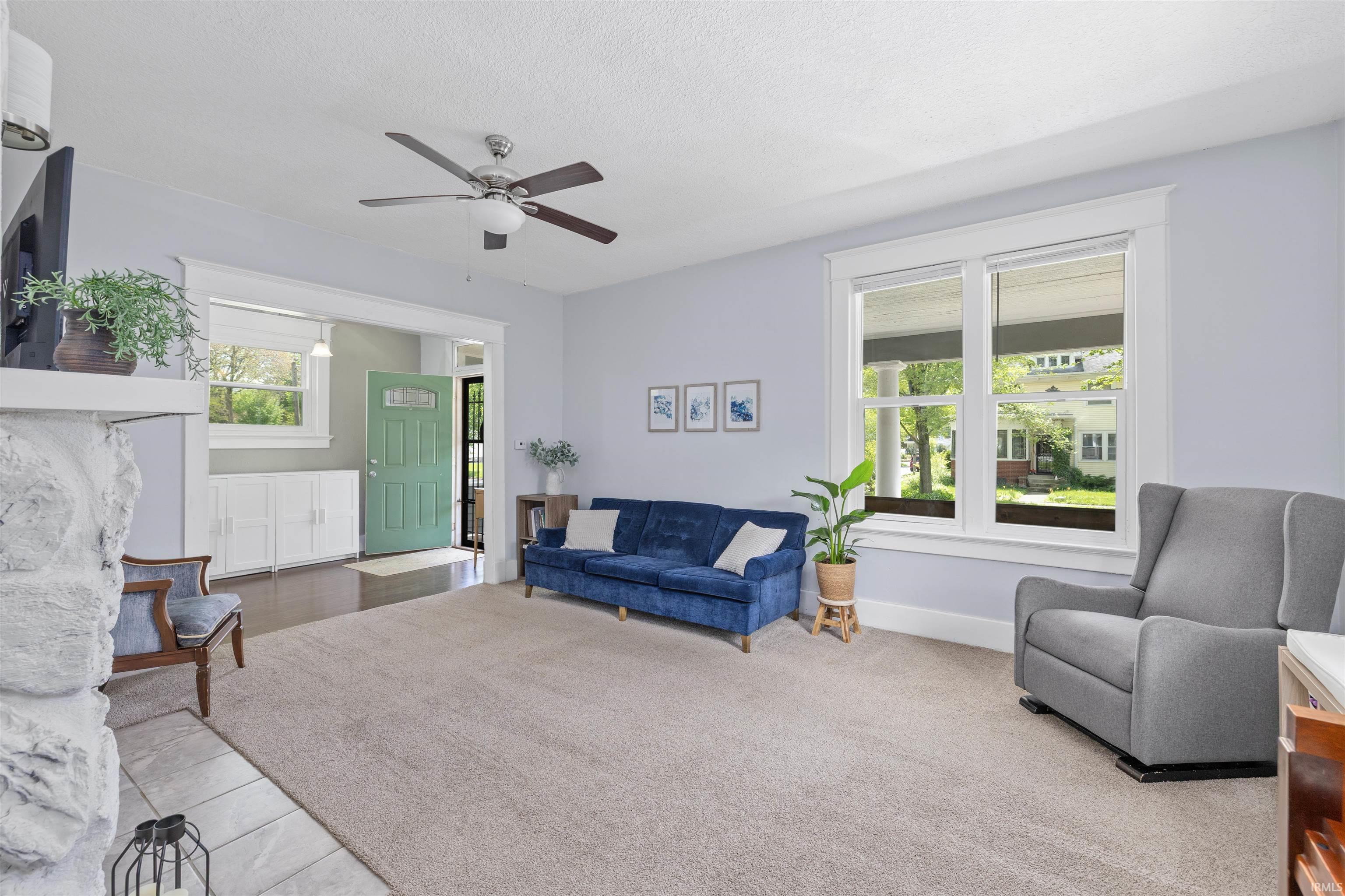 Spacious living area featuring light blue walls, white trim, and a ceiling fan