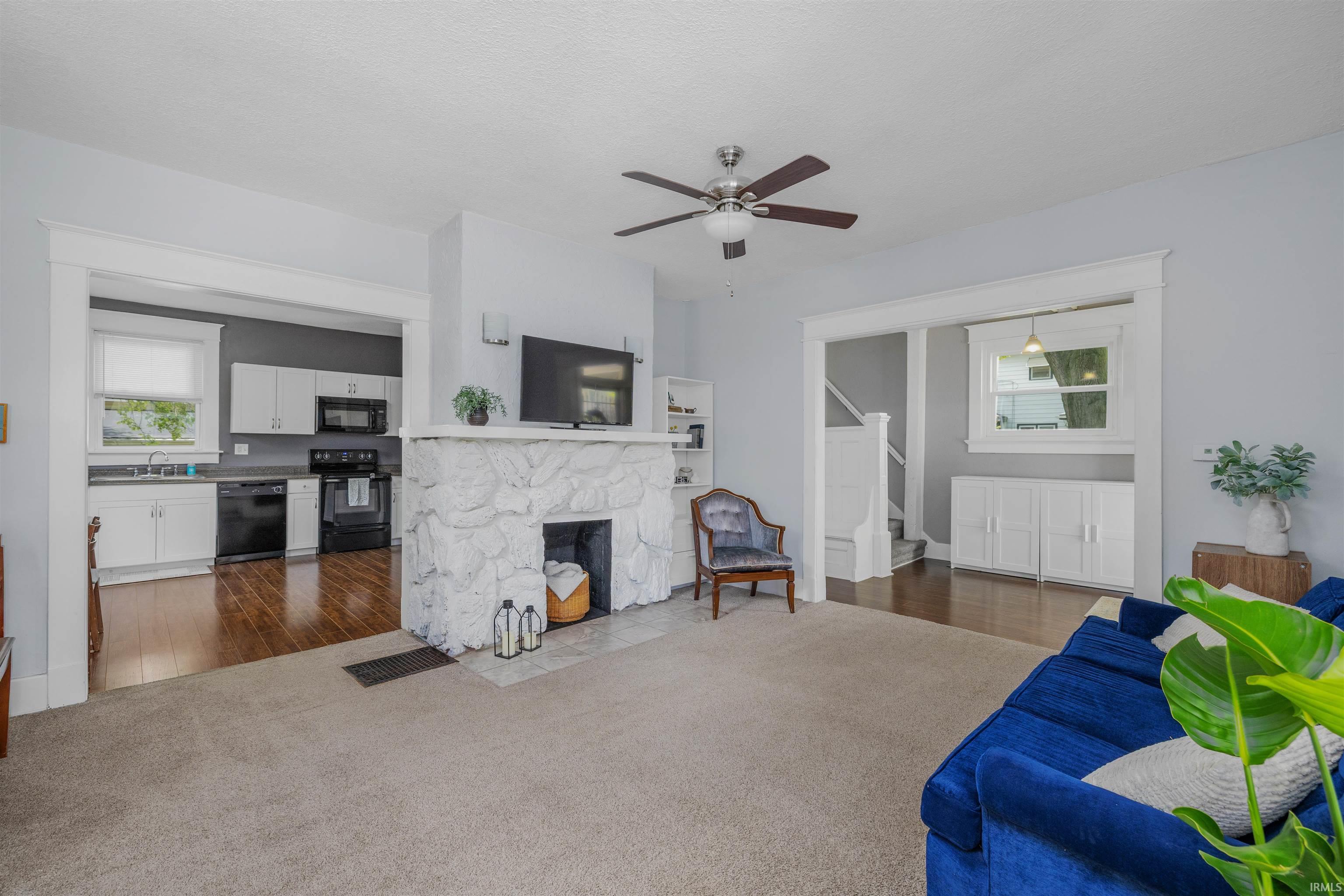 Living area featuring a stone-clad fireplace and ceiling fan