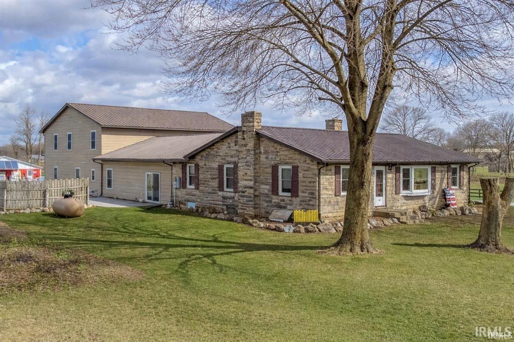 Stone facade residence featuring a brown metal roof, multiple chimneys, and coordinating shutters