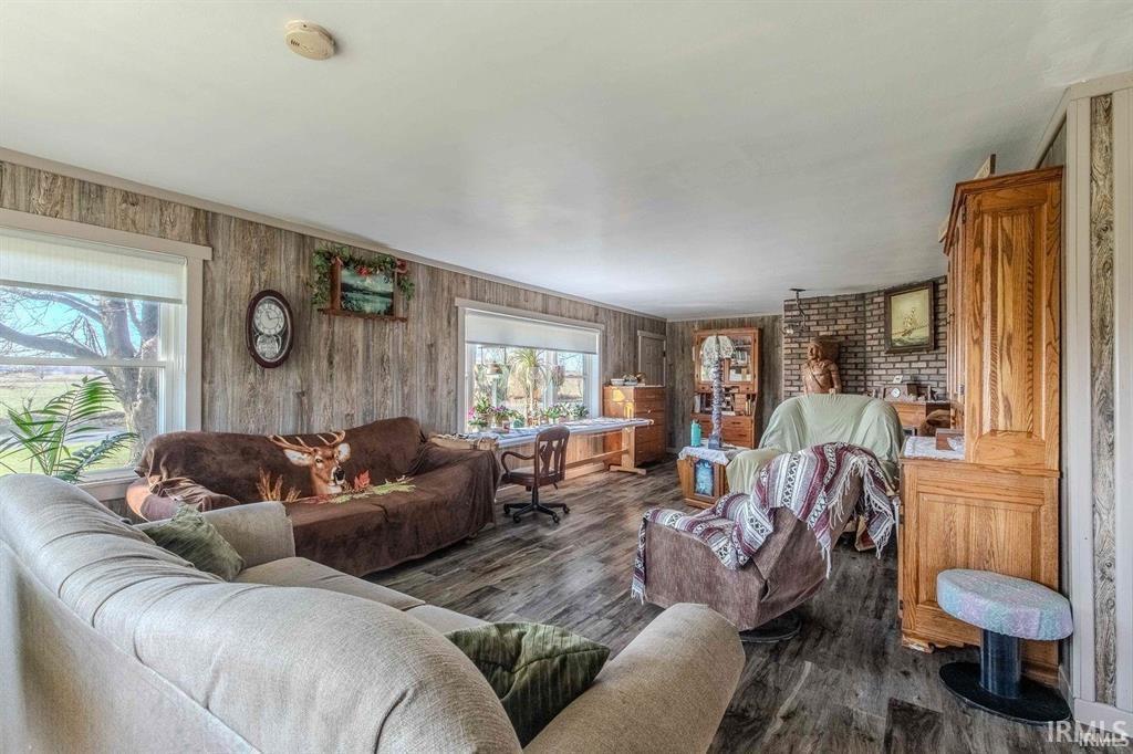 Spacious living area featuring wood-finish flooring, paneled wall accents, and an exposed brick architectural element