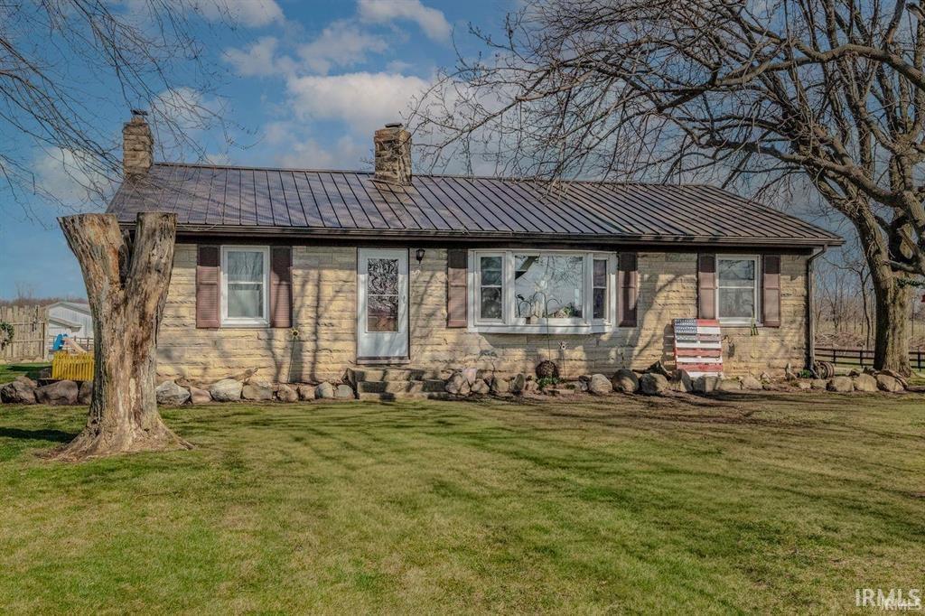 Stone facade residence with a metal roof and two brick chimneys
