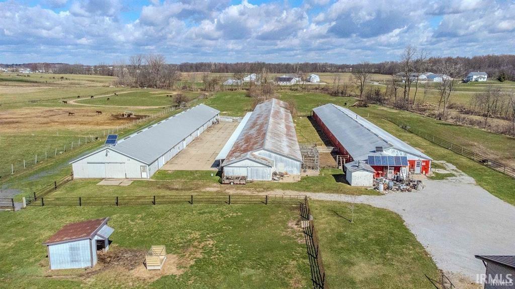 Expansive property featuring three large agricultural buildings, including a red barn with a metal roof and an additional white outbuilding
