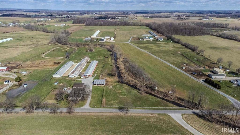 Expansive agricultural property featuring multiple outbuildings, structured farming facilities, open fields, and established road frontage