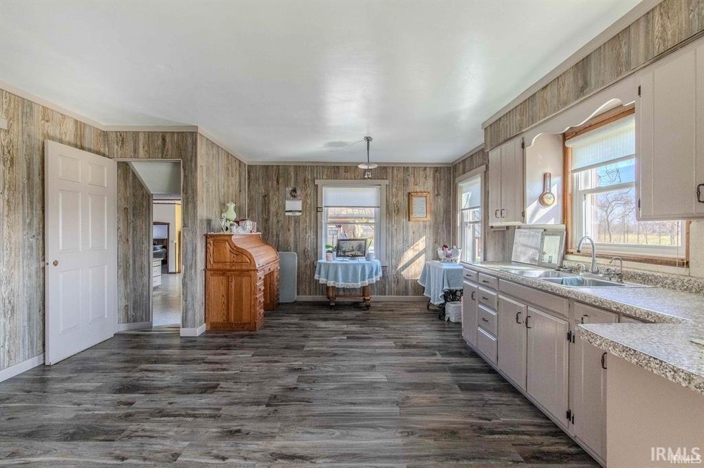 Spacious kitchen area featuring extensive wood-finish flooring, light-toned cabinetry, and ample counter space with a built-in double sink