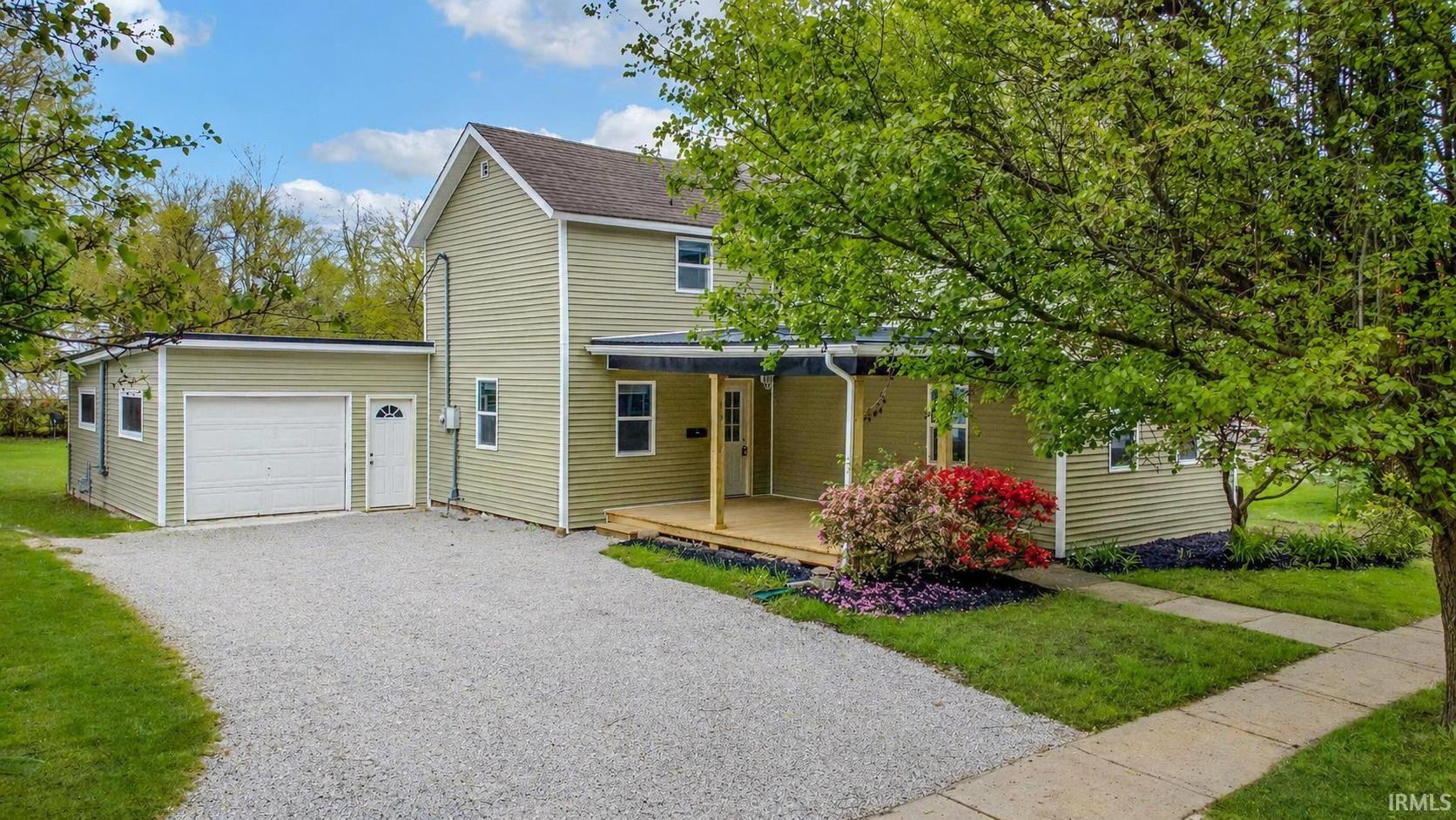 Two-story residence featuring light green siding, a gable roof, and a covered front porch with a wood-finish floor
