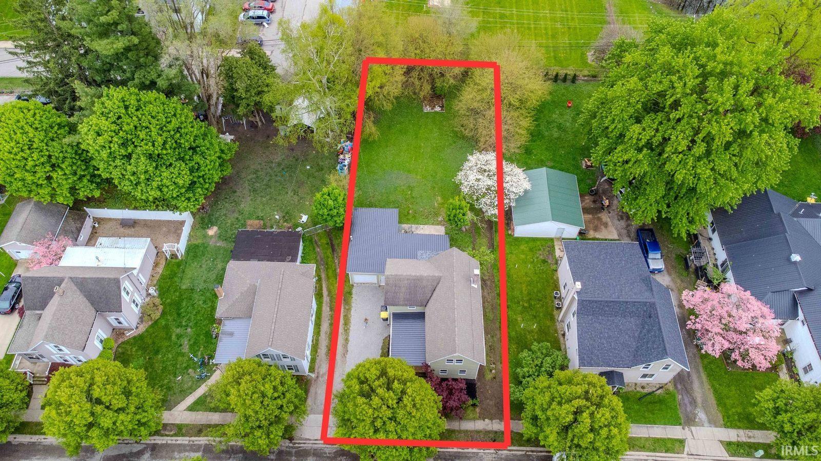 Aerial view of a residential property with an expansive green lawn