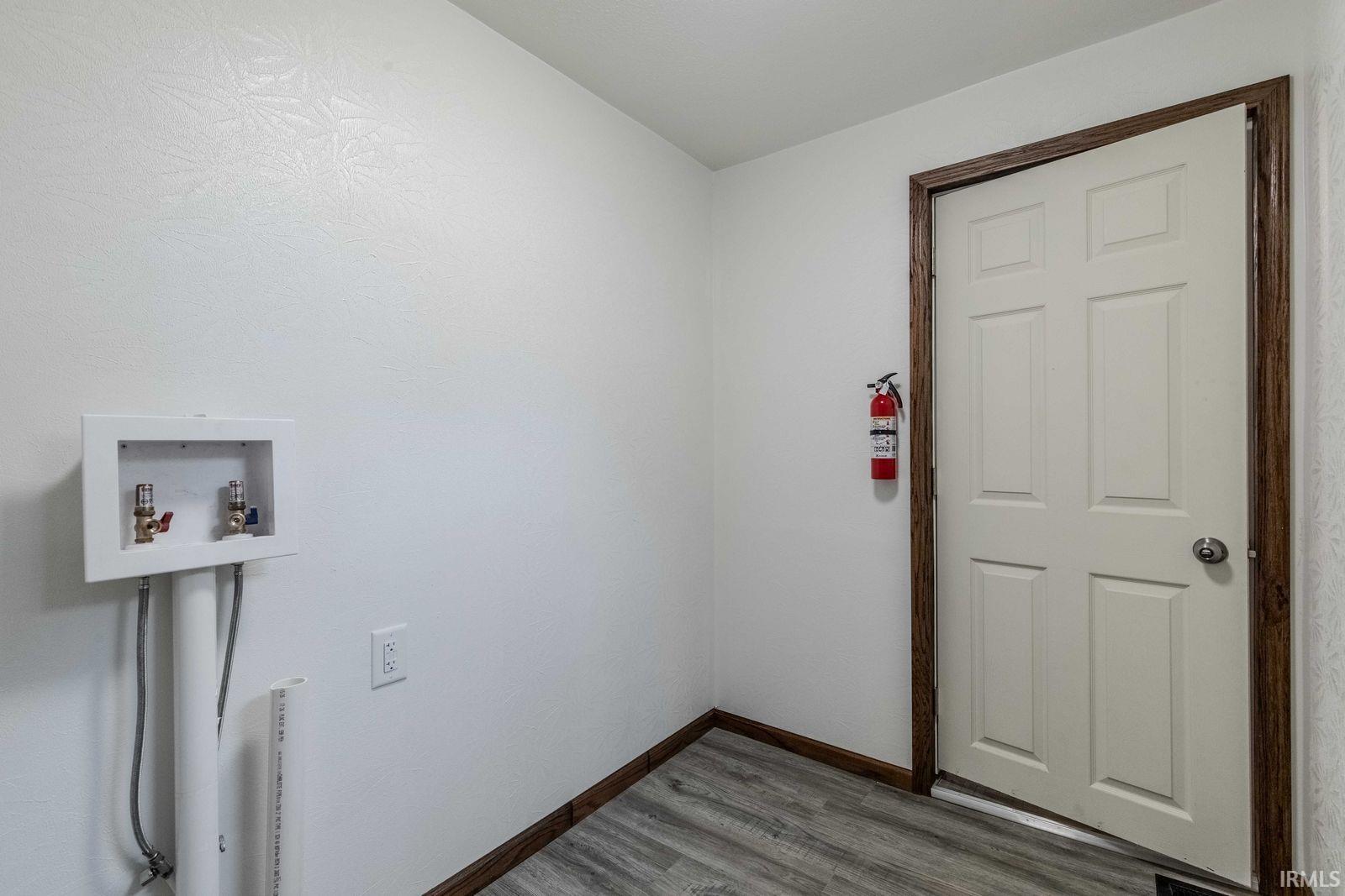 Dedicated laundry area featuring a utility box with hookups, wood-finish flooring, and white painted walls