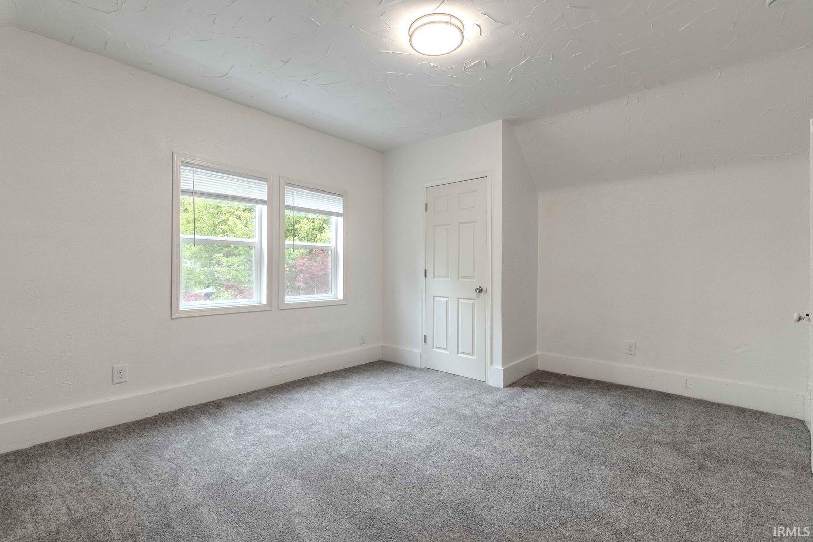 Room featuring light gray carpeting, crisp white walls, and a recessed ceiling light
