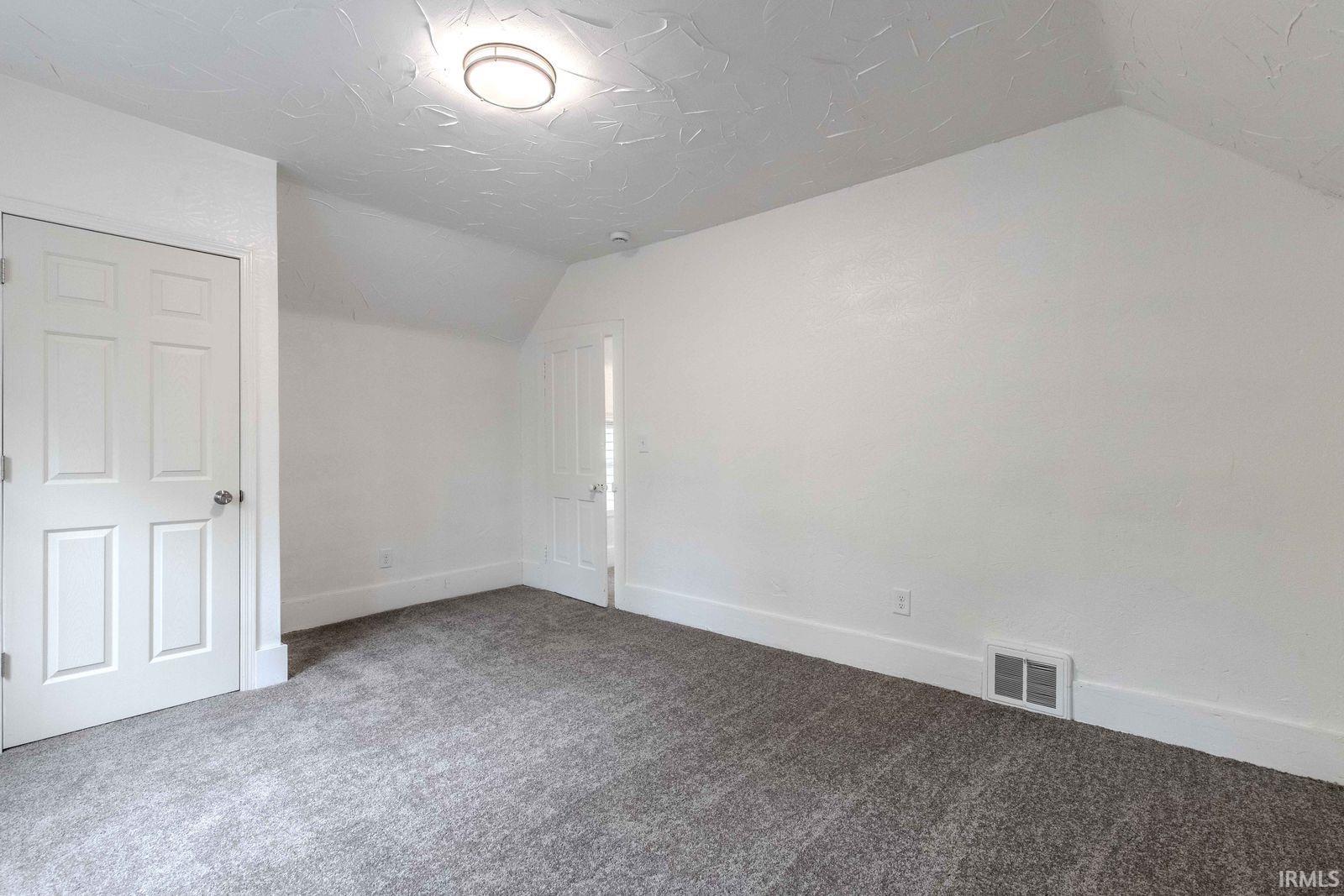 Carpeted room with white walls, white trim, and a textured ceiling