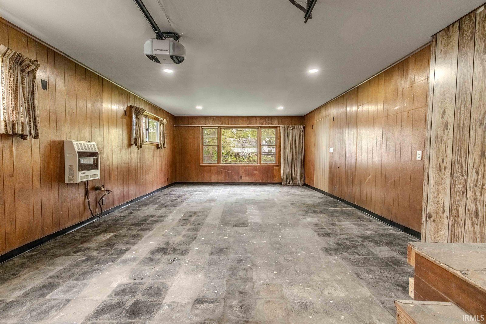 Spacious room featuring wood-panel walls, multiple windows, recessed lighting, and a ceiling-mounted projector
