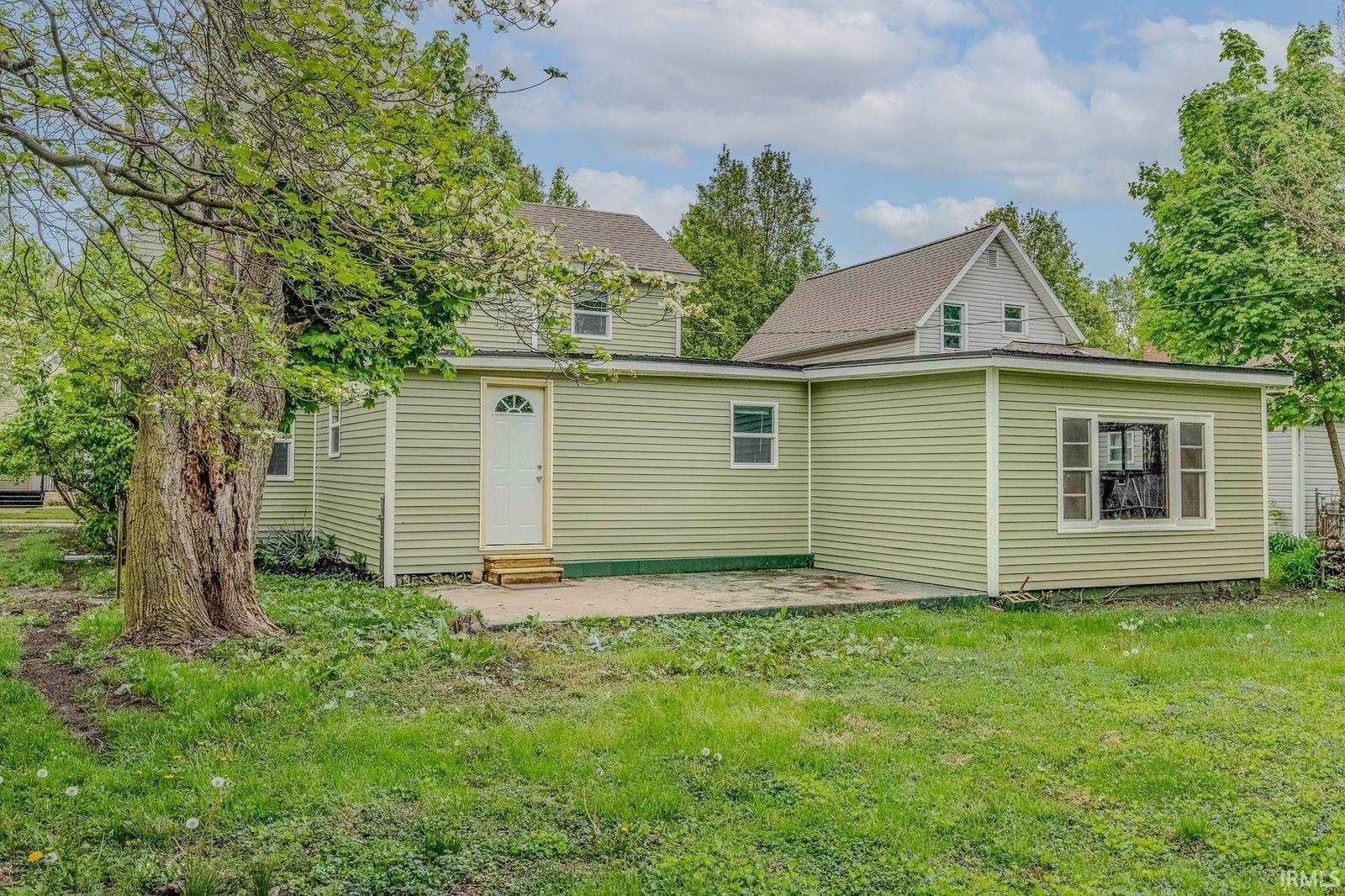 Rear exterior featuring light green horizontal siding and a white entry door with an arched window