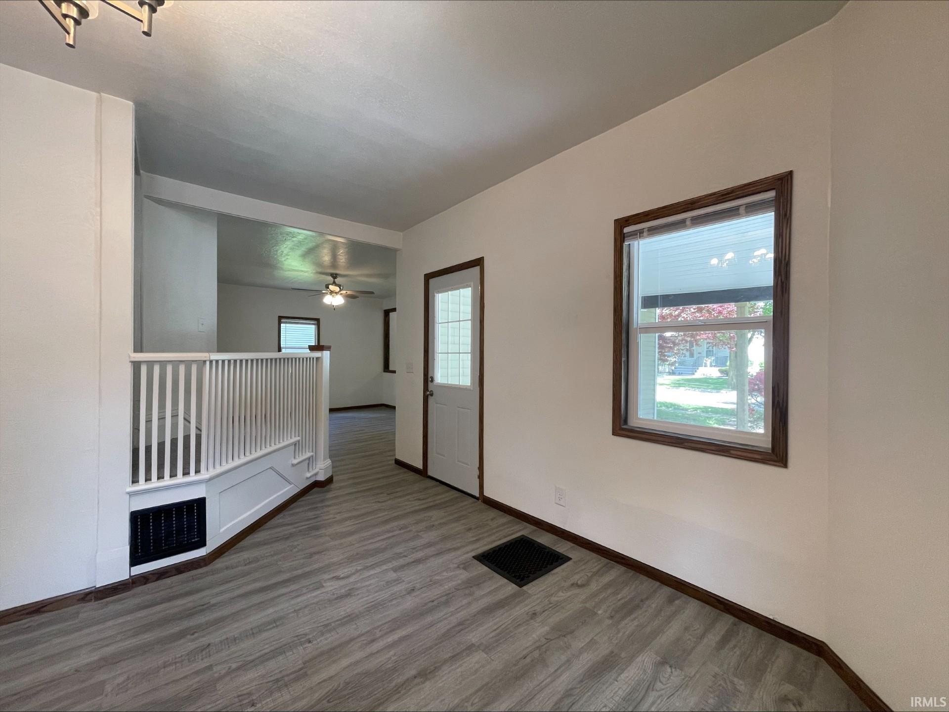 Entryway featuring wood-finish flooring, white walls, and a white interior door with clear glass panels