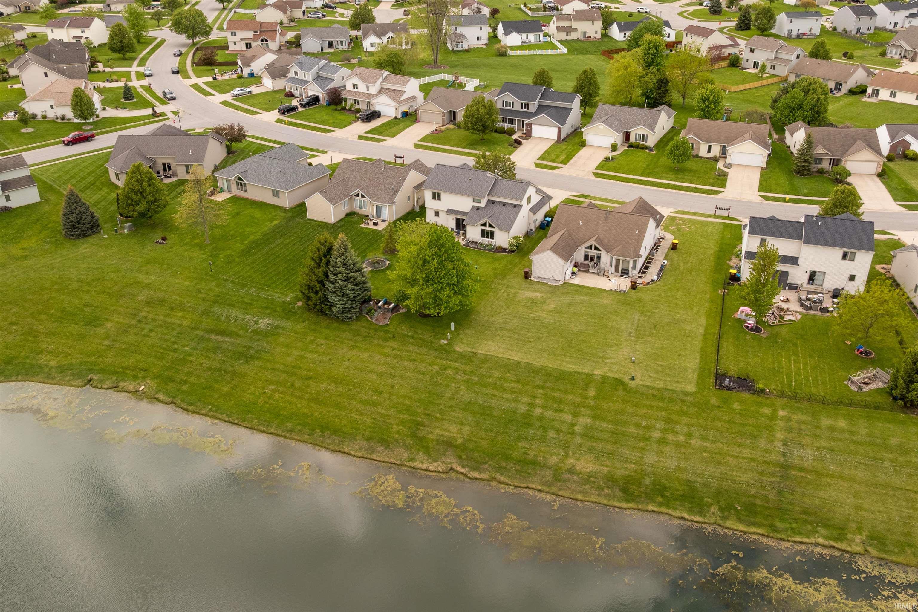 Expansive water frontage property featuring a large green lawn, mature trees, and a spacious backyard patio